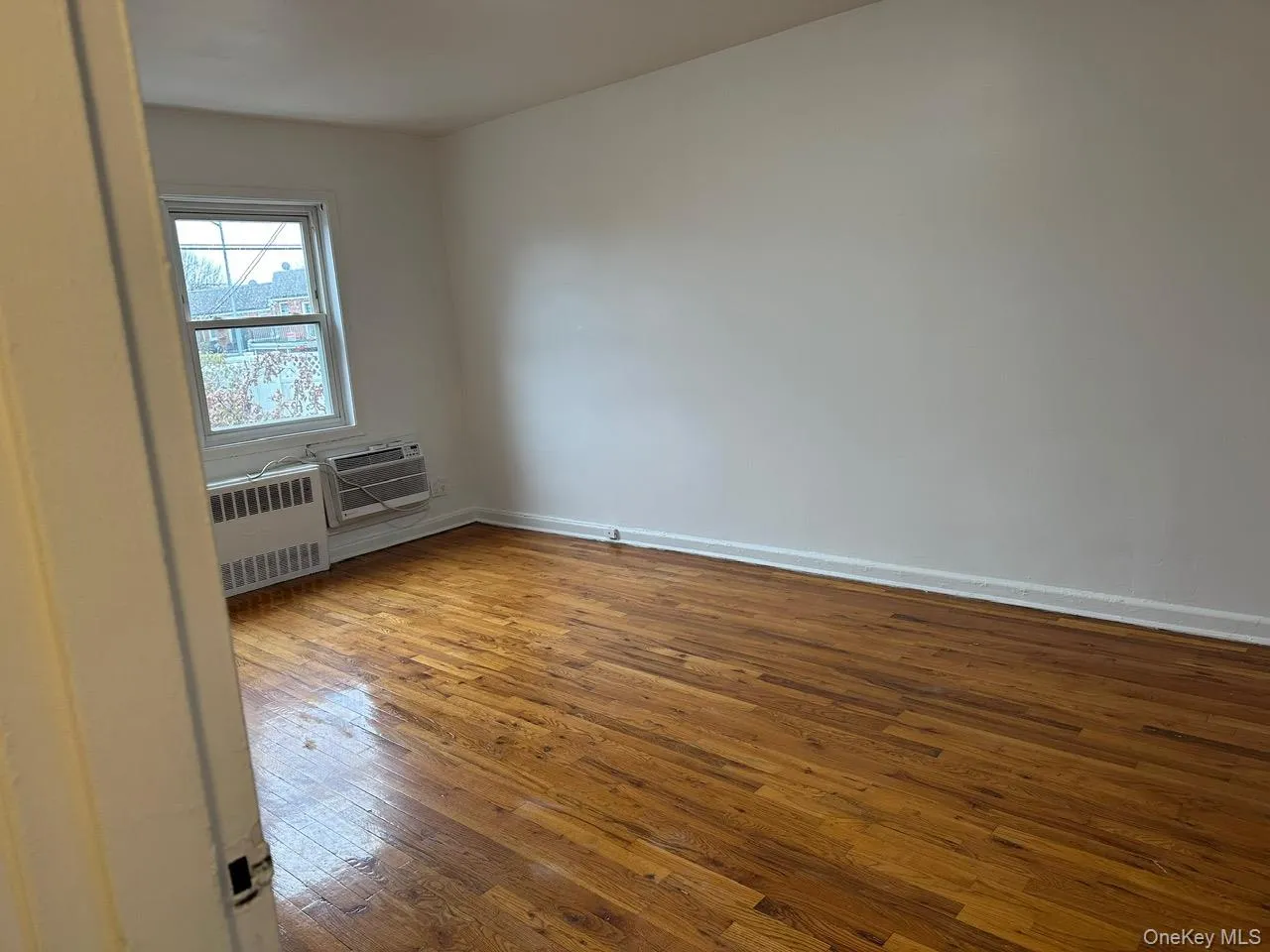 Spare room with hardwood / wood-style floors and radiator heating unit Spare room with hardwood / wood-style floors and radiator heating unit