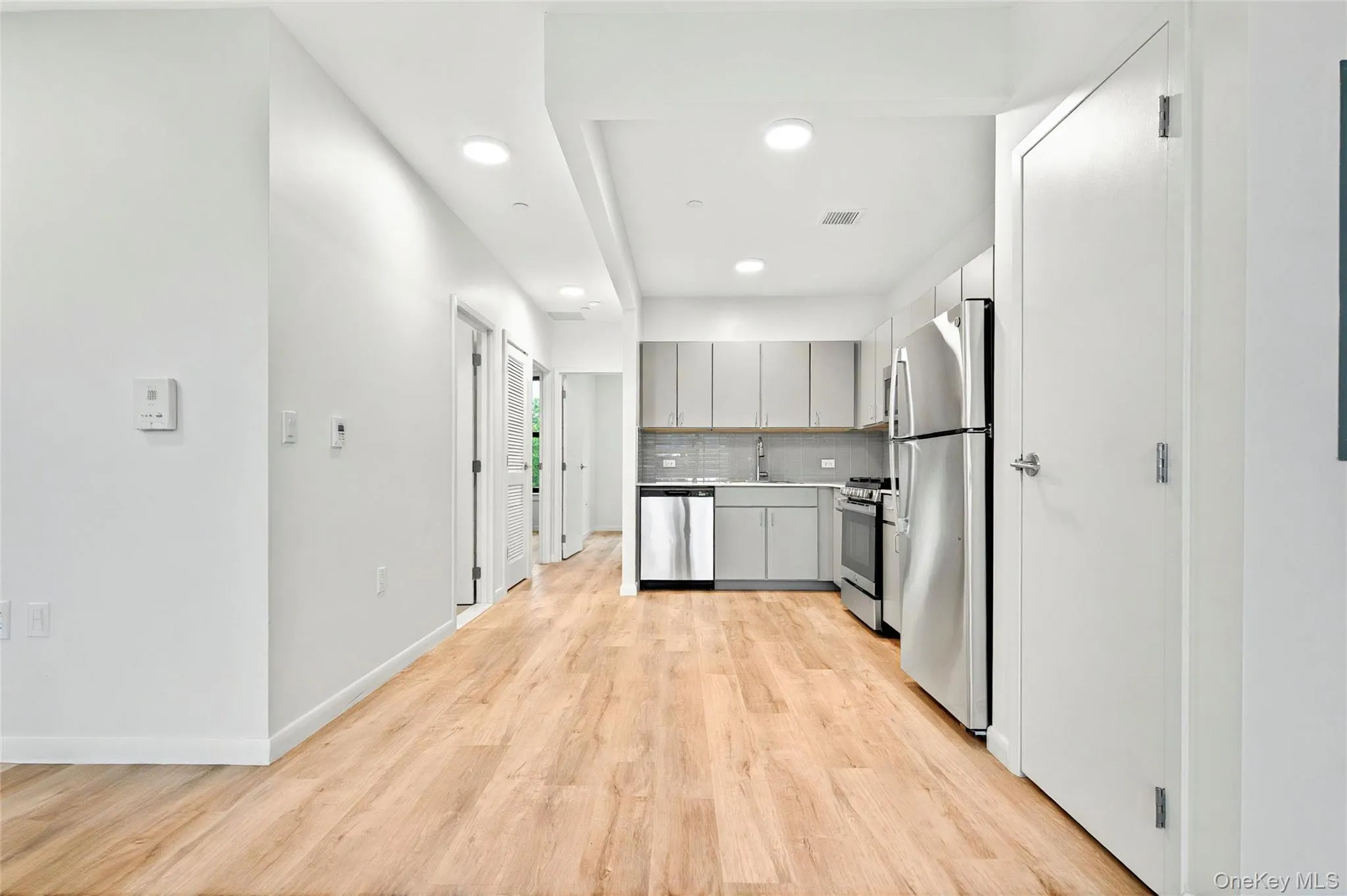 Kitchen featuring appliances with stainless steel finishes, gray cabinets, a sink, light wood-type flooring, and recessed lighting Kitchen featuring appliances with stainless steel finishes, gray cabinets, a sink, light wood-type flooring, and recessed lighting