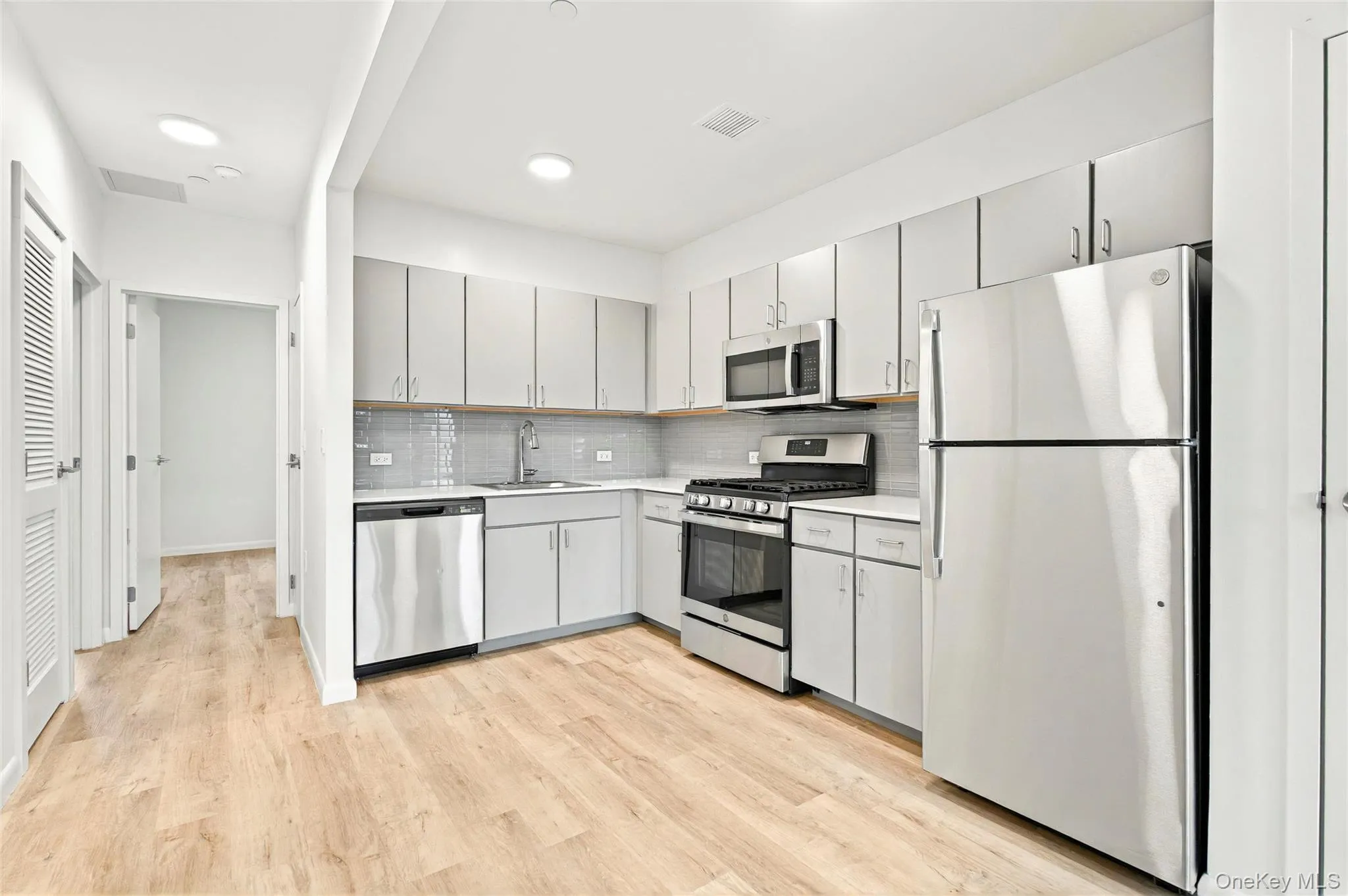 Kitchen showing stainless steel refrigerator, stove, microwave and dishwasher and hallway to the bedrooms Kitchen showing stainless steel refrigerator, stove, microwave and dishwasher and hallway to the bedrooms