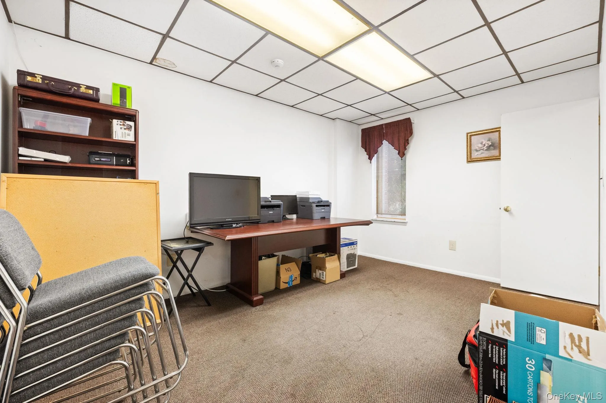 Office area featuring light carpet and a paneled ceiling Office area featuring light carpet and a paneled ceiling