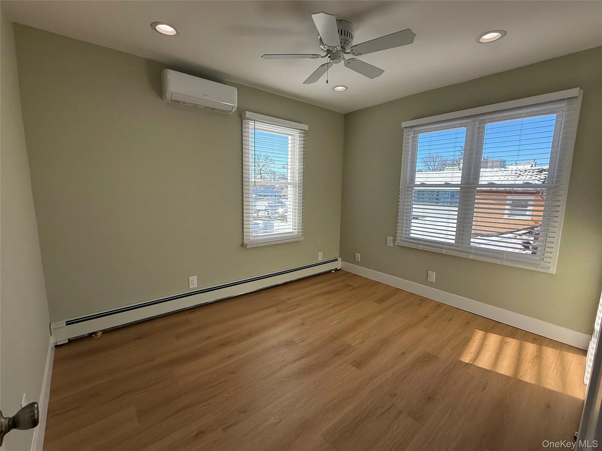 Unfurnished room featuring a baseboard radiator, light wood-style floors, a wall unit AC, recessed lighting, and a ceiling fan Unfurnished room featuring a baseboard radiator, light wood-style floors, a wall unit AC, recessed lighting, and a ceiling fan