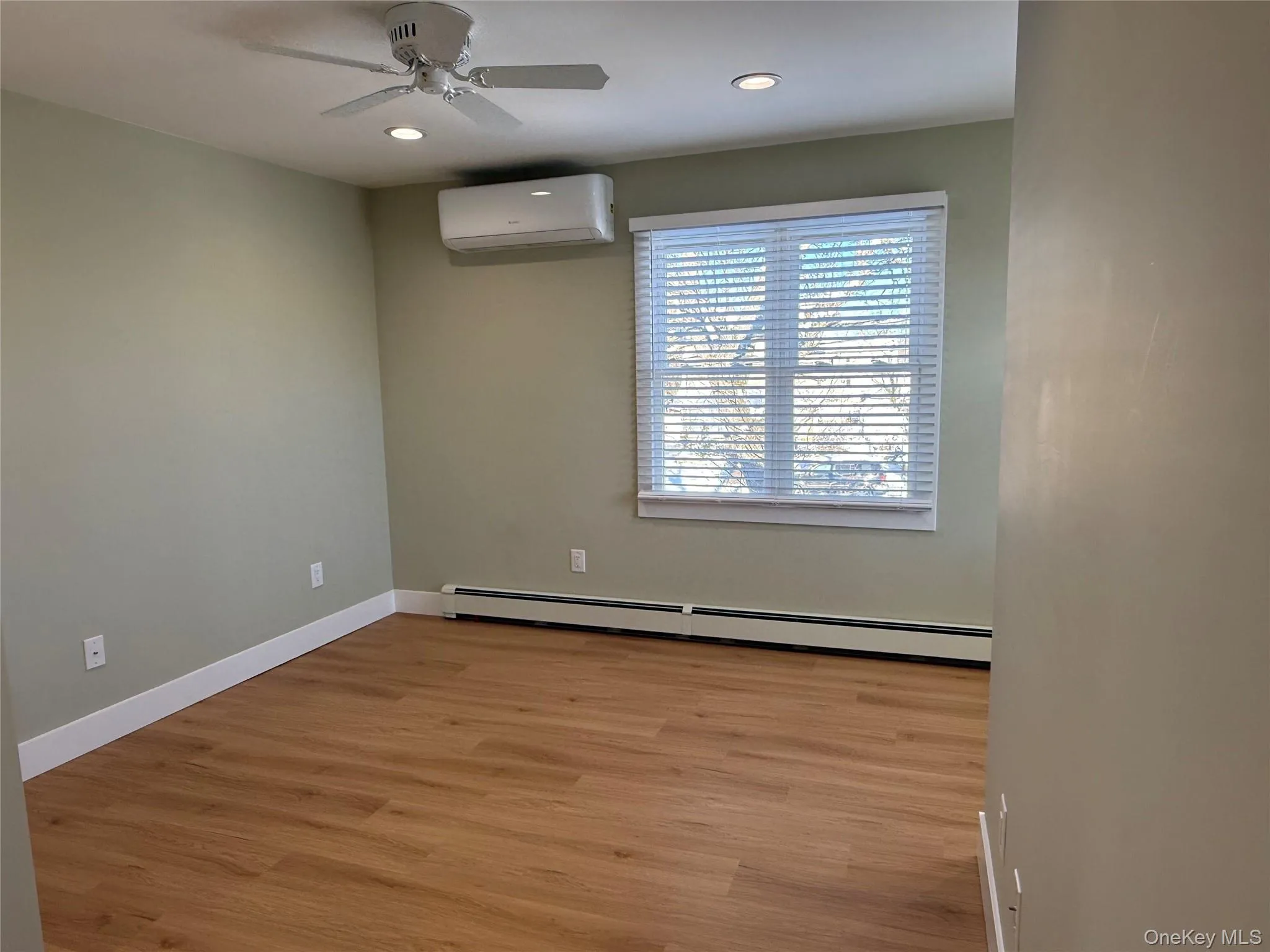 Unfurnished room featuring a baseboard heating unit, light wood-type flooring, a wall unit AC, recessed lighting, and ceiling fan Unfurnished room featuring a baseboard heating unit, light wood-type flooring, a wall unit AC, recessed lighting, and ceiling fan