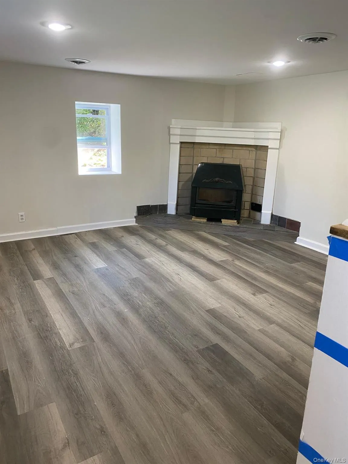 Unfurnished living room with wood finished floors, a brick fireplace, and recessed lighting Unfurnished living room with wood finished floors, a brick fireplace, and recessed lighting