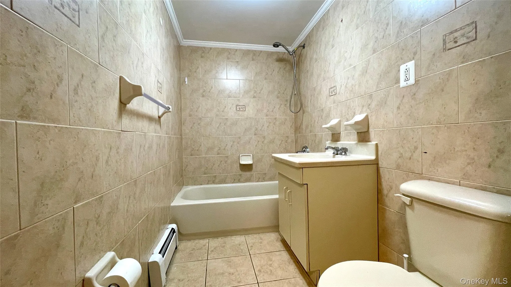 Bathroom featuring crown molding, tile walls, vanity, baseboard heating, and light tile patterned flooring Bathroom featuring crown molding, tile walls, vanity, baseboard heating, and light tile patterned flooring
