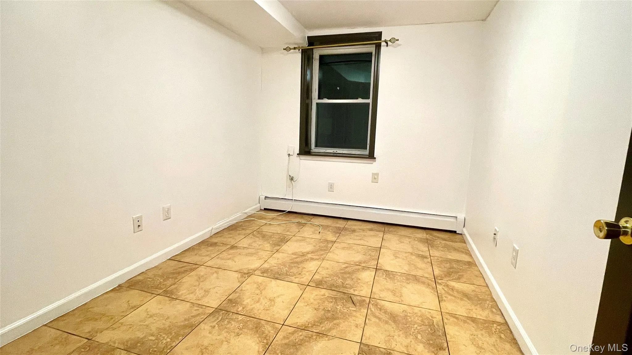Empty room featuring baseboard heating and light tile patterned floors Empty room featuring baseboard heating and light tile patterned floors