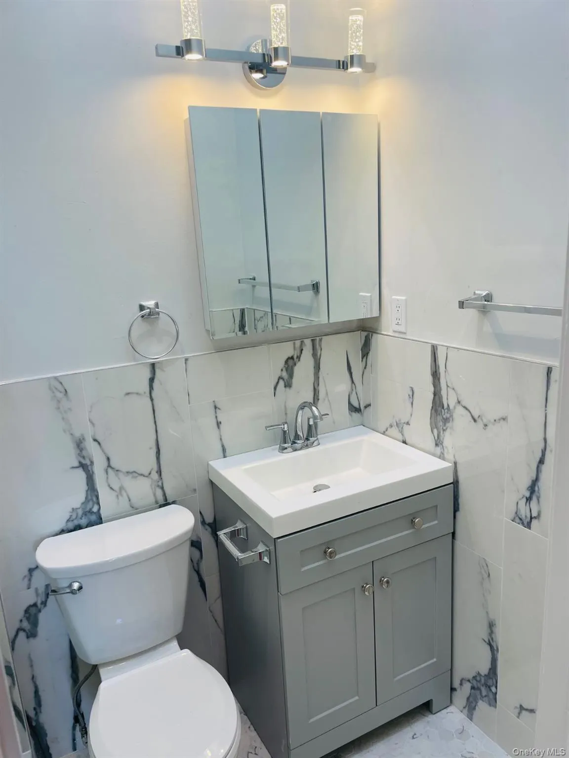 Half bathroom with tile walls, a wainscoted wall, and vanity Half bathroom with tile walls, a wainscoted wall, and vanity