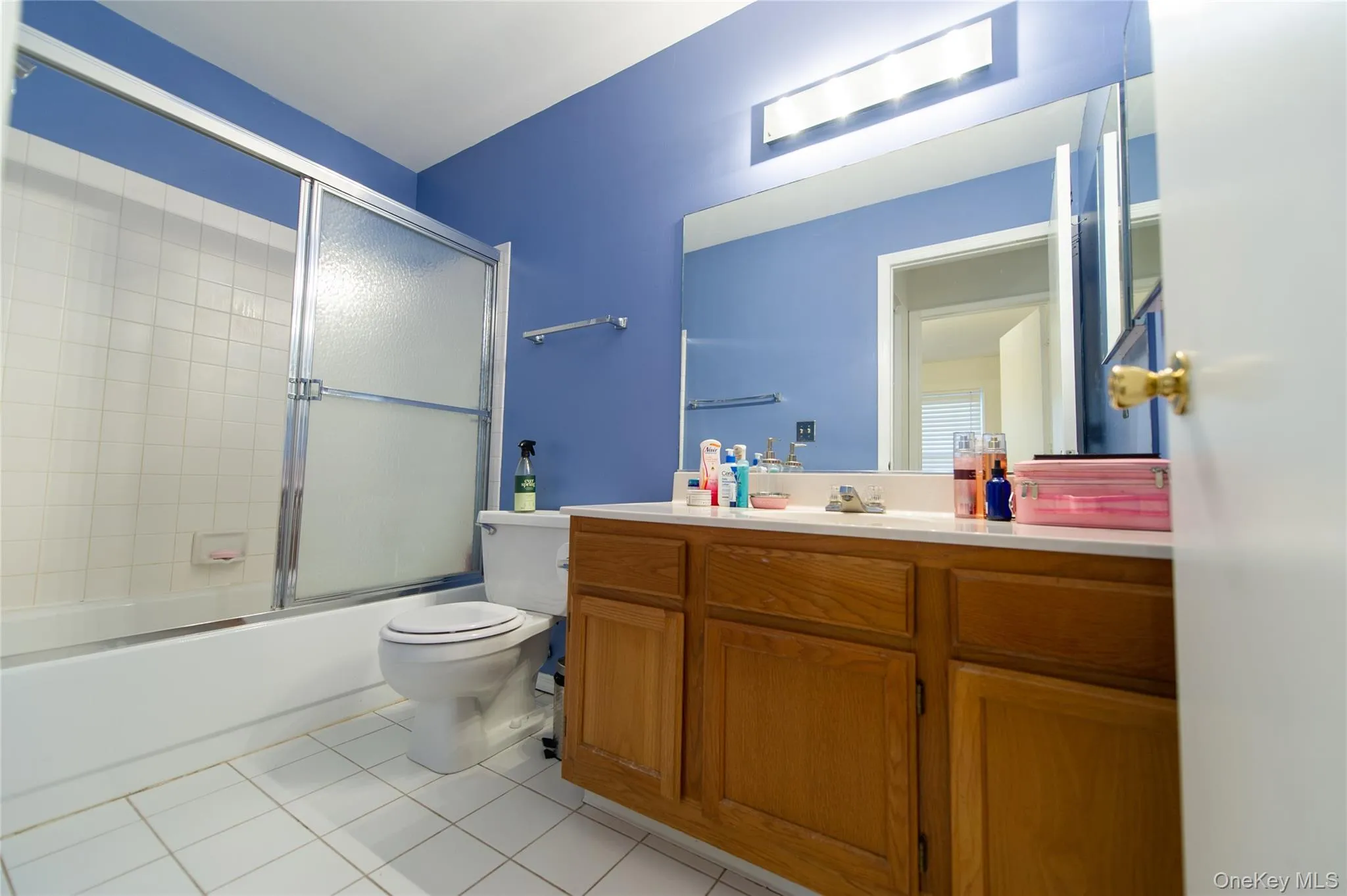 Bathroom featuring vanity, shower / bath combination with glass door, and light tile patterned floors Bathroom featuring vanity, shower / bath combination with glass door, and light tile patterned floors