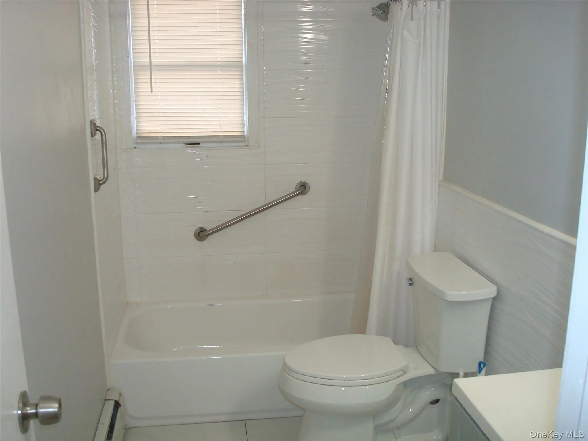 Full bathroom featuring vanity, baseboard heating, tile patterned flooring, and shower / bathtub combination with curtain Full bathroom featuring vanity, baseboard heating, tile patterned flooring, and shower / bathtub combination with curtain