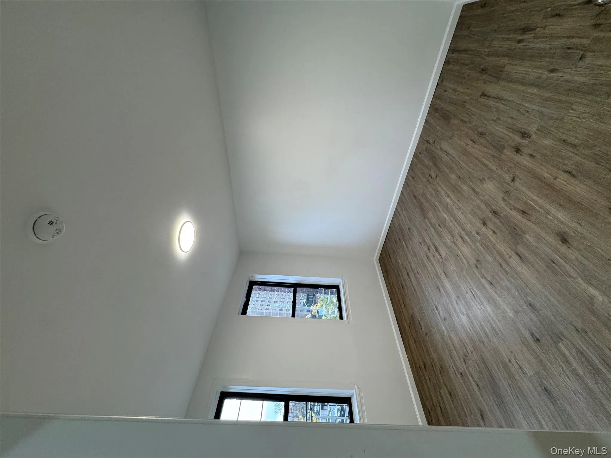 Empty room with dark wood-style flooring and a smoke detector Empty room with dark wood-style flooring and a smoke detector
