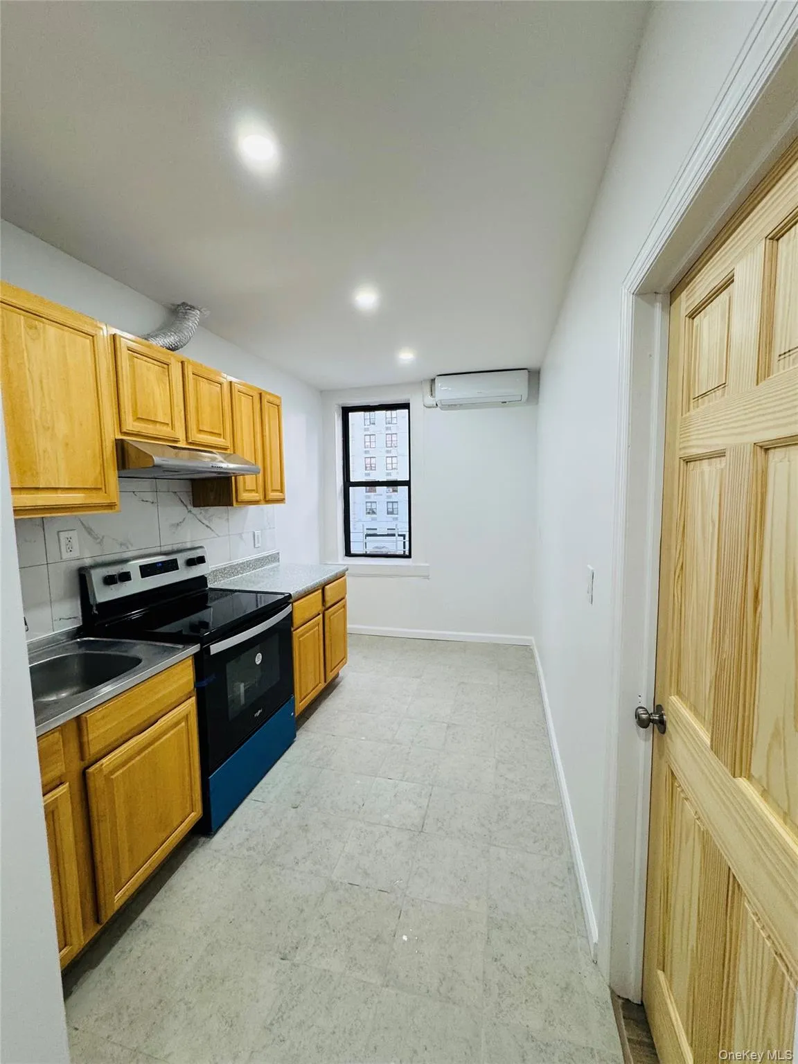 Kitchen with electric range oven, decorative backsplash, recessed lighting, and under cabinet range hood Kitchen with electric range oven, decorative backsplash, recessed lighting, and under cabinet range hood