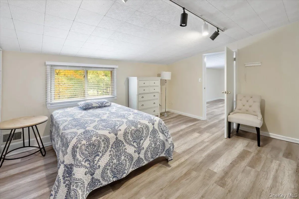Bedroom with light wood-type flooring and rail lighting Bedroom with light wood-type flooring and rail lighting
