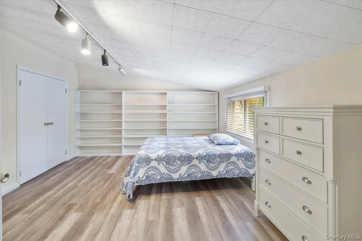 Bedroom featuring vaulted ceiling, light wood-style flooring, and rail lighting Bedroom featuring vaulted ceiling, light wood-style flooring, and rail lighting