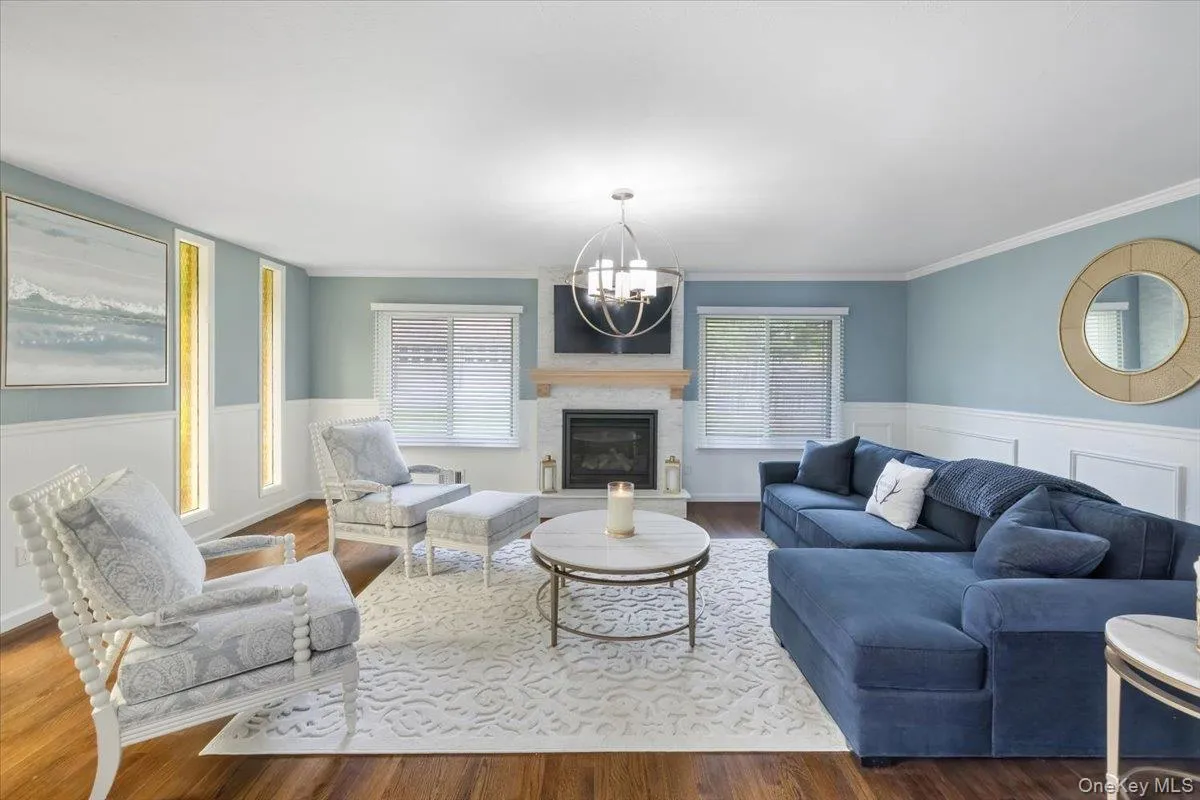 Living area with a glass covered fireplace, wainscoting, wood finished floors, and a chandelier Living area with a glass covered fireplace, wainscoting, wood finished floors, and a chandelier