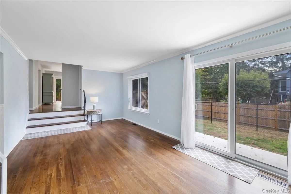 Unfurnished living room featuring hardwood / wood-style flooring, stairway, ornamental molding, and plenty of natural light Unfurnished living room featuring hardwood / wood-style flooring, stairway, ornamental molding, and plenty of natural light