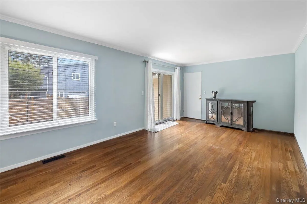 Unfurnished living room featuring plenty of natural light, ornamental molding, and wood finished floors Unfurnished living room featuring plenty of natural light, ornamental molding, and wood finished floors