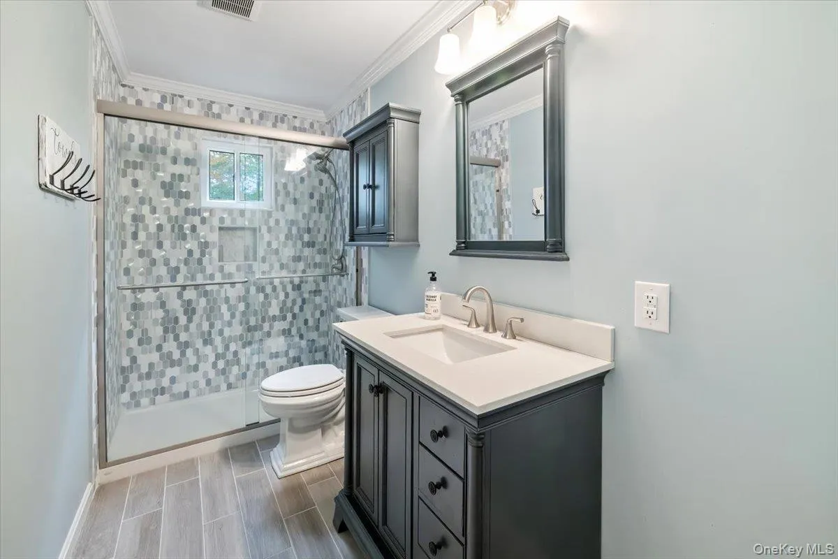 Bathroom with vanity, a shower stall, and crown molding Bathroom with vanity, a shower stall, and crown molding