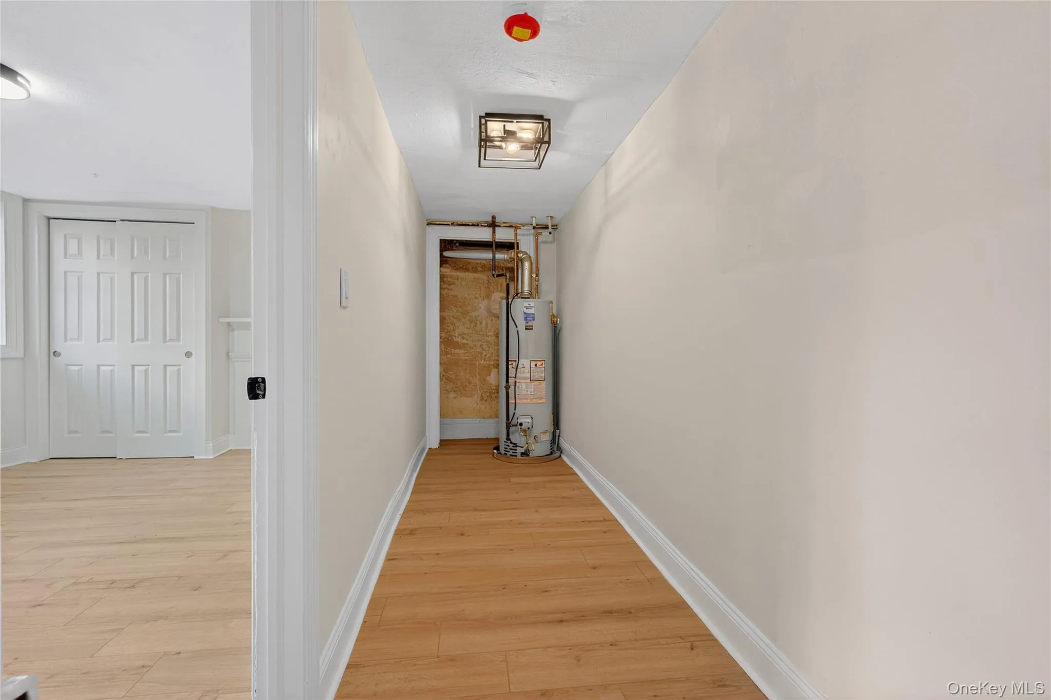 Hall with light wood-type flooring and water heater Hall with light wood-type flooring and water heater