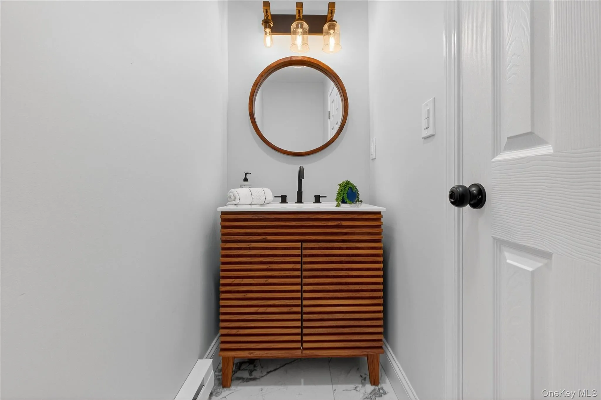Bathroom featuring marble finish floors, vanity, and baseboard heating Bathroom featuring marble finish floors, vanity, and baseboard heating