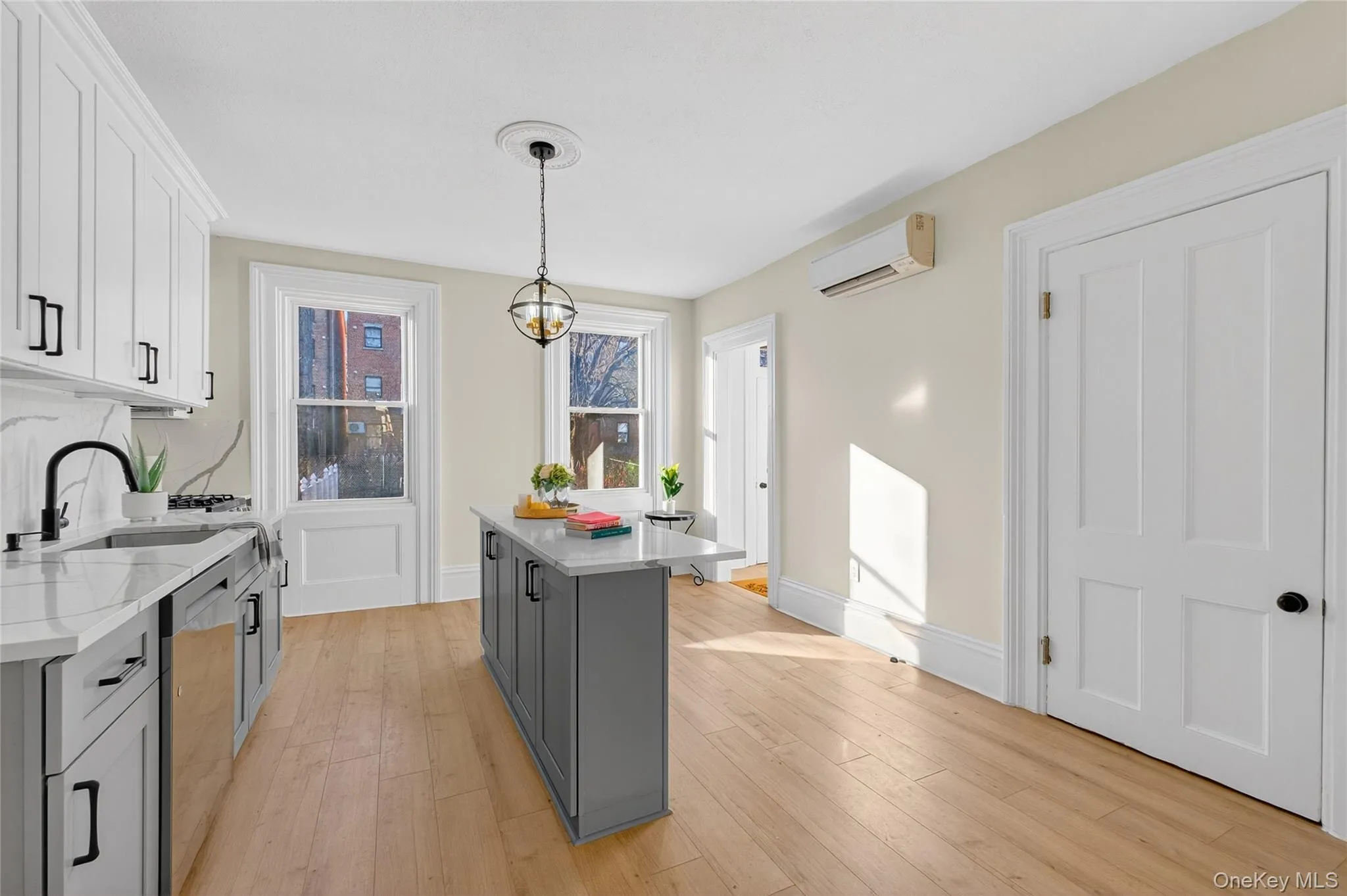 Kitchen featuring gray cabinets, hanging light fixtures, light stone countertops, and light wood-style flooring Kitchen featuring gray cabinets, hanging light fixtures, light stone countertops, and light wood-style flooring