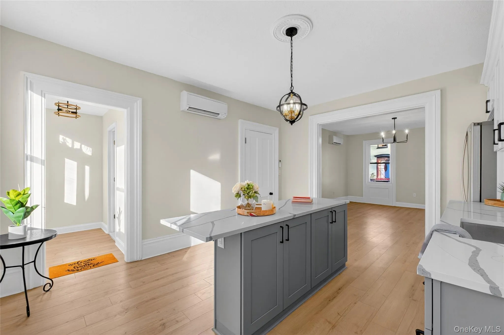 Kitchen with gray cabinets, light stone countertops, pendant lighting, light wood-type flooring, and a chandelier Kitchen with gray cabinets, light stone countertops, pendant lighting, light wood-type flooring, and a chandelier