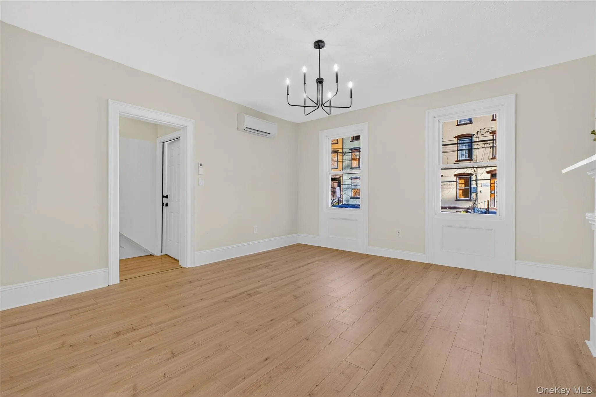 Unfurnished dining area with light wood-style flooring, a chandelier, and an AC wall unit Unfurnished dining area with light wood-style flooring, a chandelier, and an AC wall unit