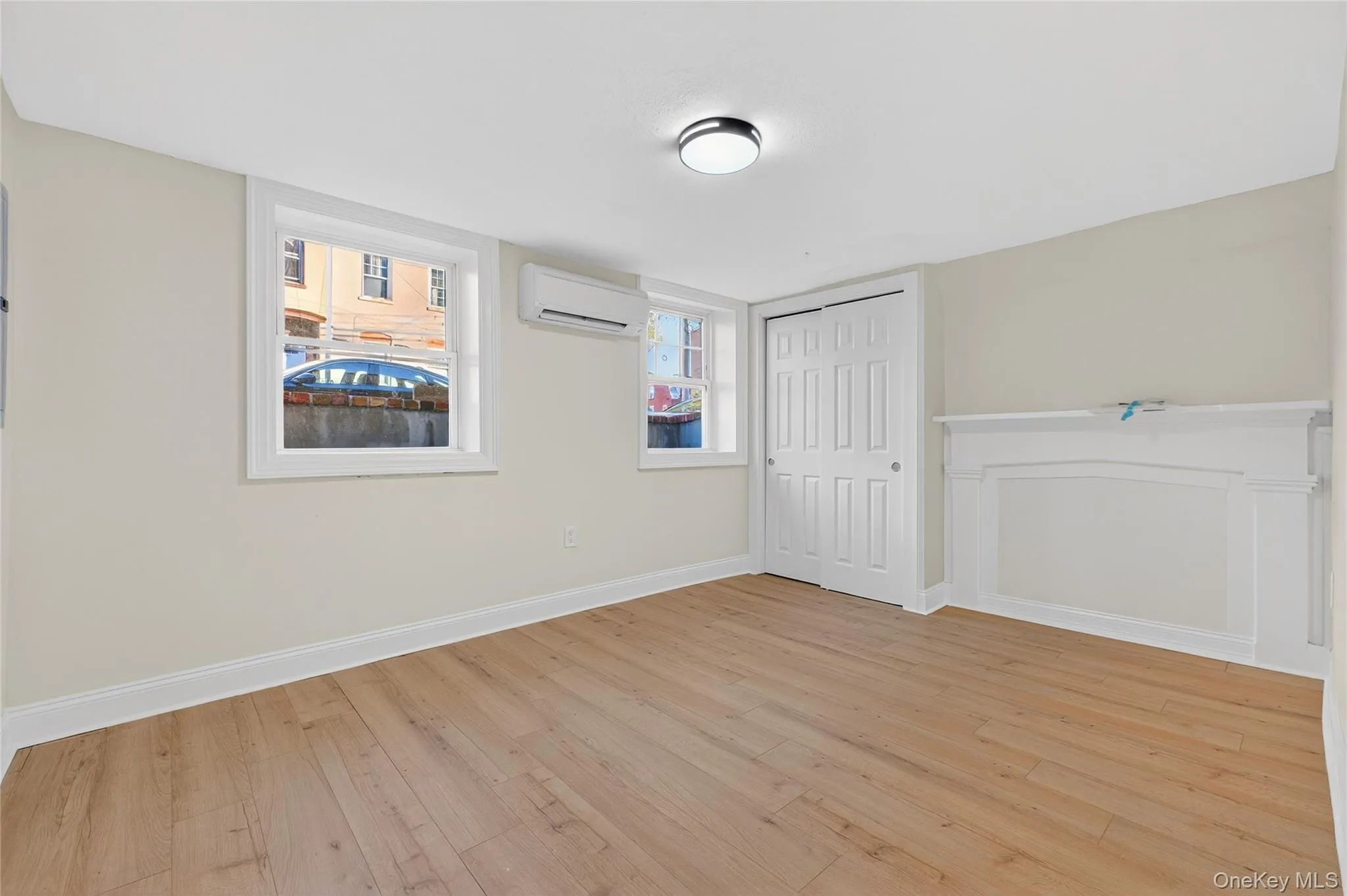 Unfurnished bedroom with light wood finished floors, a closet, and a wall mounted AC Unfurnished bedroom with light wood finished floors, a closet, and a wall mounted AC