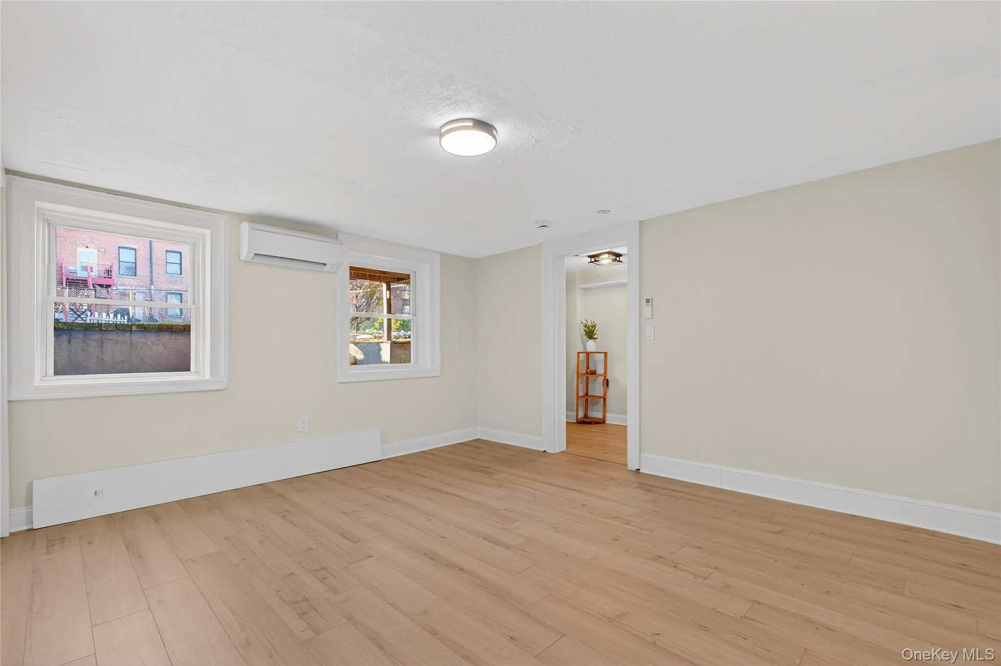 Unfurnished room with light wood finished floors and an AC wall unit Unfurnished room with light wood finished floors and an AC wall unit