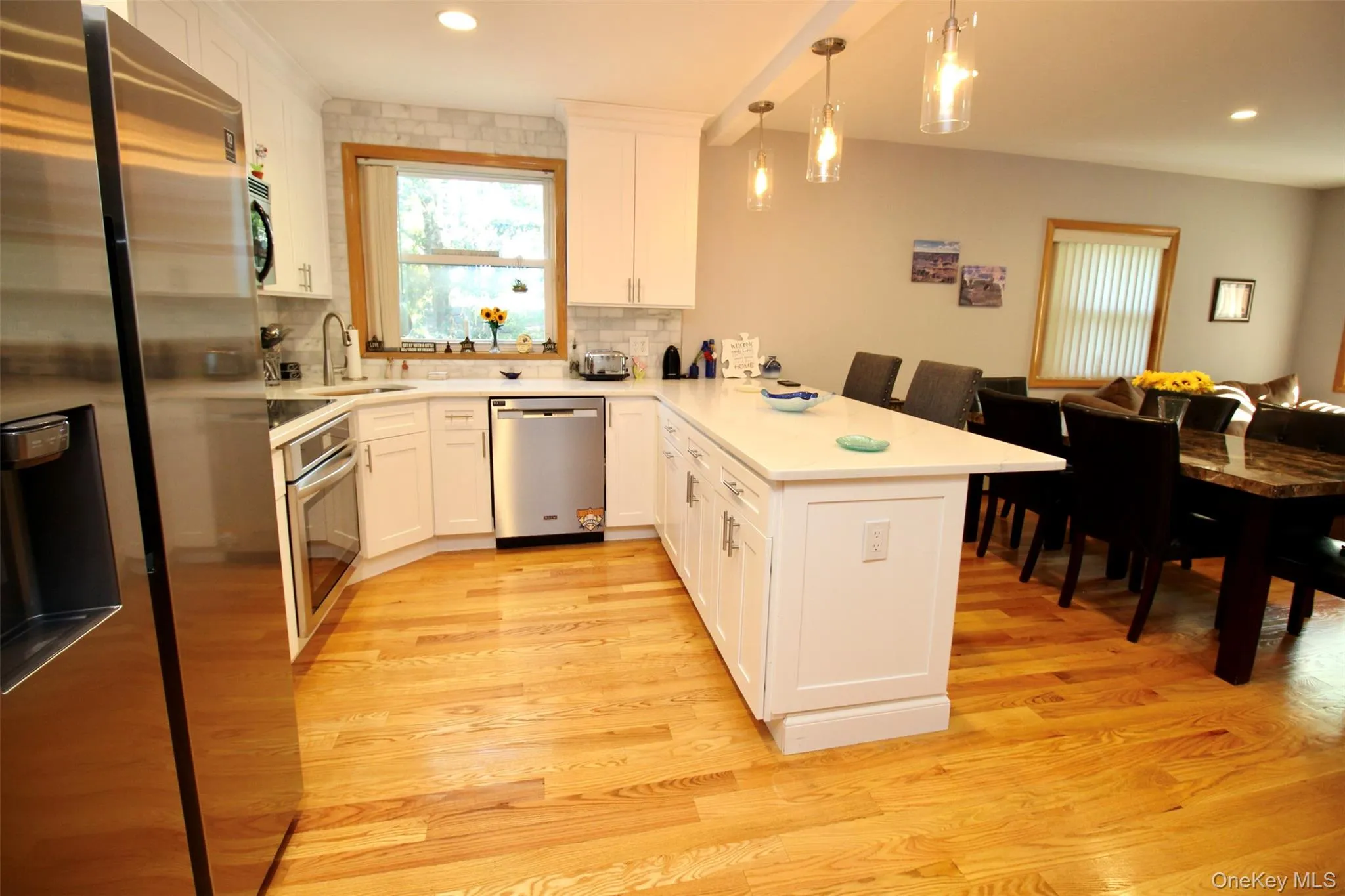 Kitchen with stainless steel appliances, a peninsula, white cabinetry, pendant lighting, and recessed lighting Kitchen with stainless steel appliances, a peninsula, white cabinetry, pendant lighting, and recessed lighting