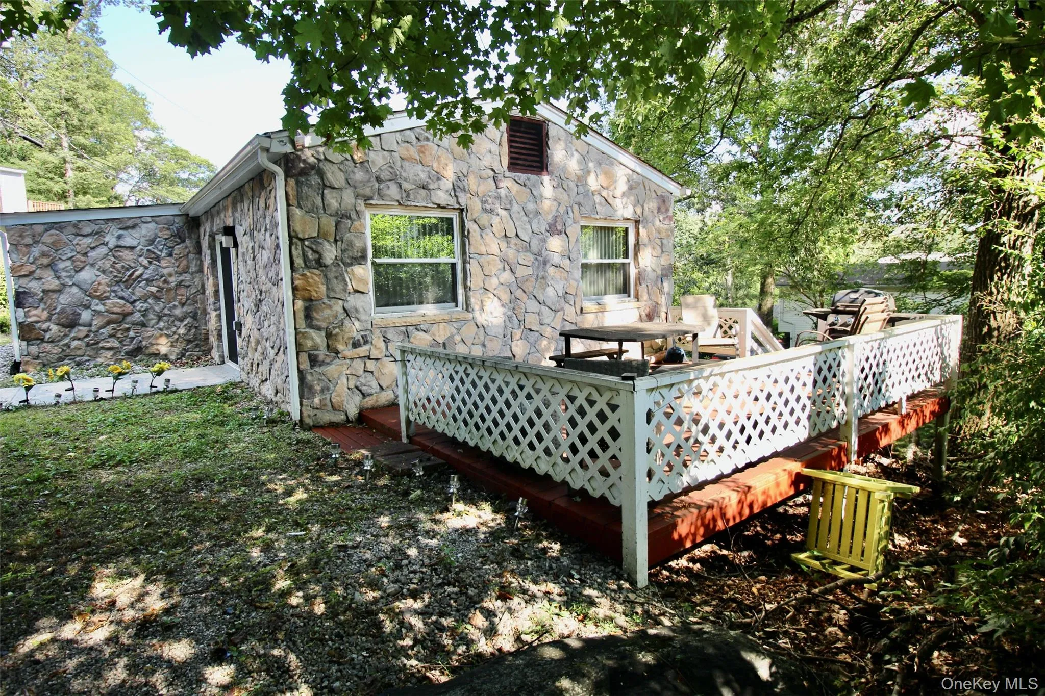 Rear view of property featuring stone siding and a wooden deck Rear view of property featuring stone siding and a wooden deck