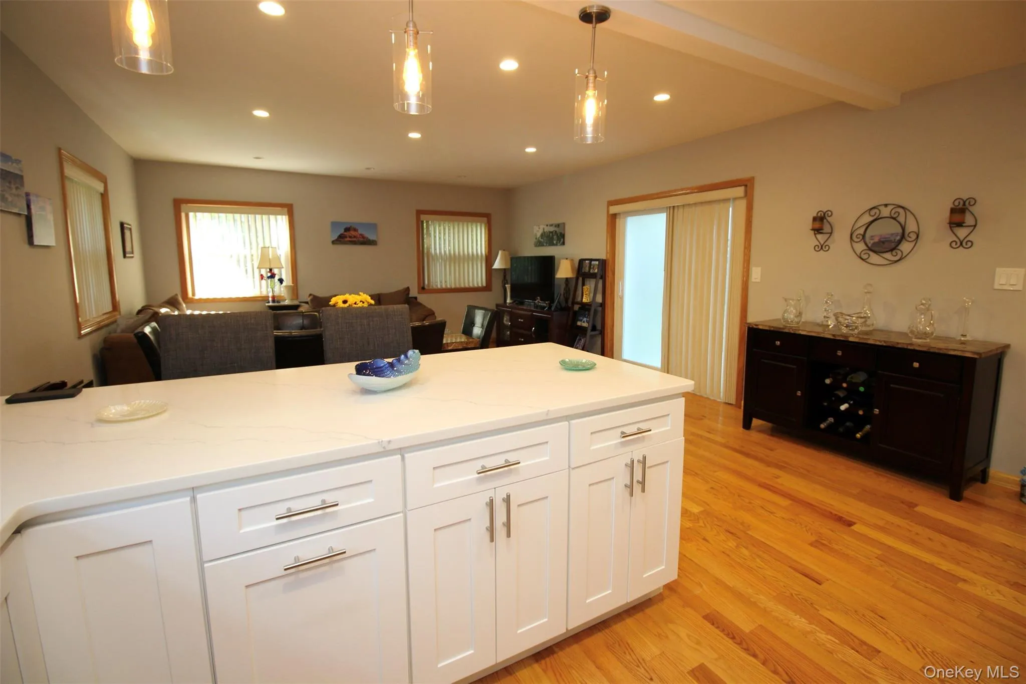 Kitchen with decorative light fixtures, open floor plan, white cabinets, light wood finished floors, and recessed lighting Kitchen with decorative light fixtures, open floor plan, white cabinets, light wood finished floors, and recessed lighting