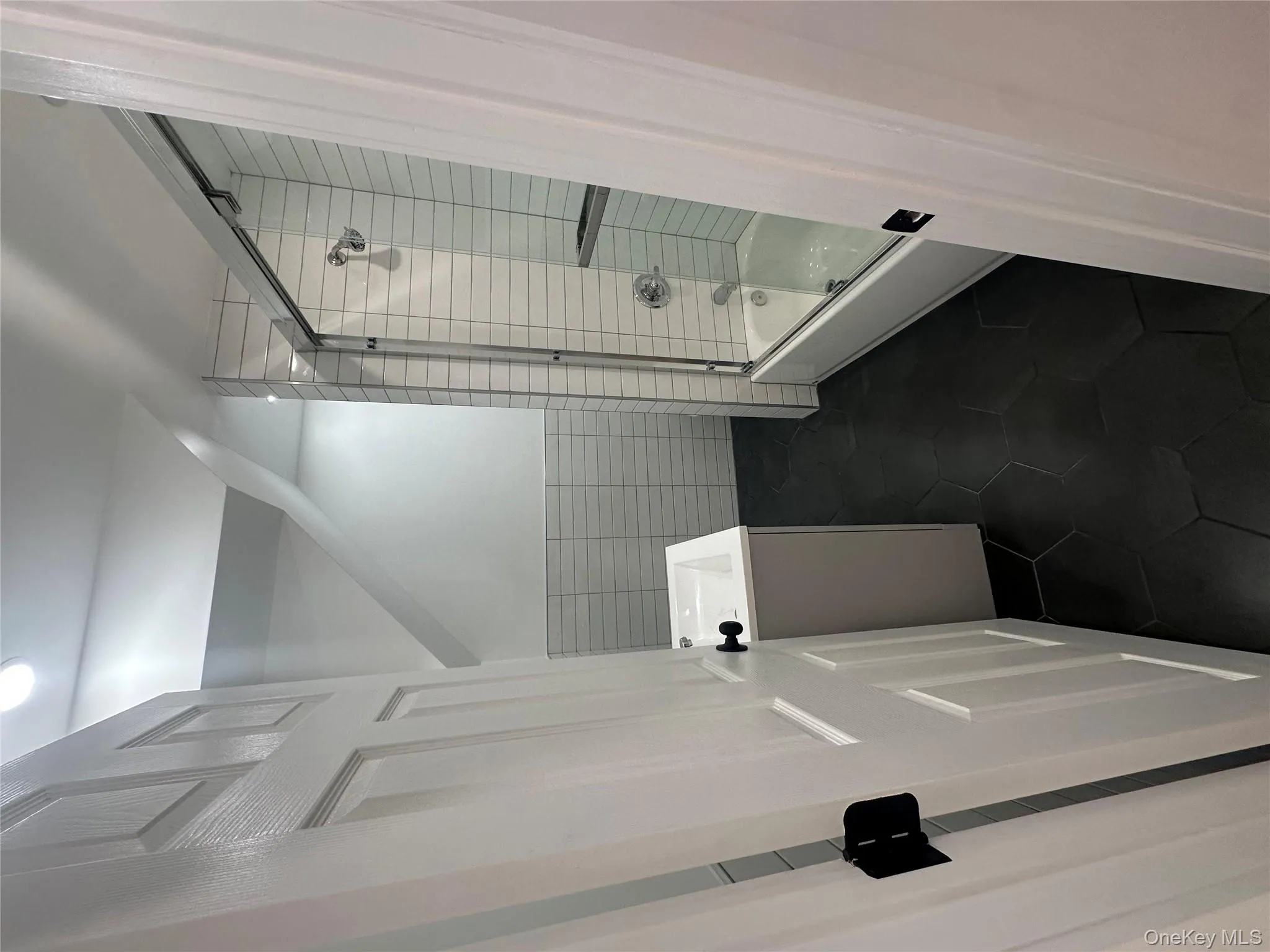 Full bathroom featuring vanity, dark tile patterned flooring, enclosed tub / shower combo, and tile walls Full bathroom featuring vanity, dark tile patterned flooring, enclosed tub / shower combo, and tile walls