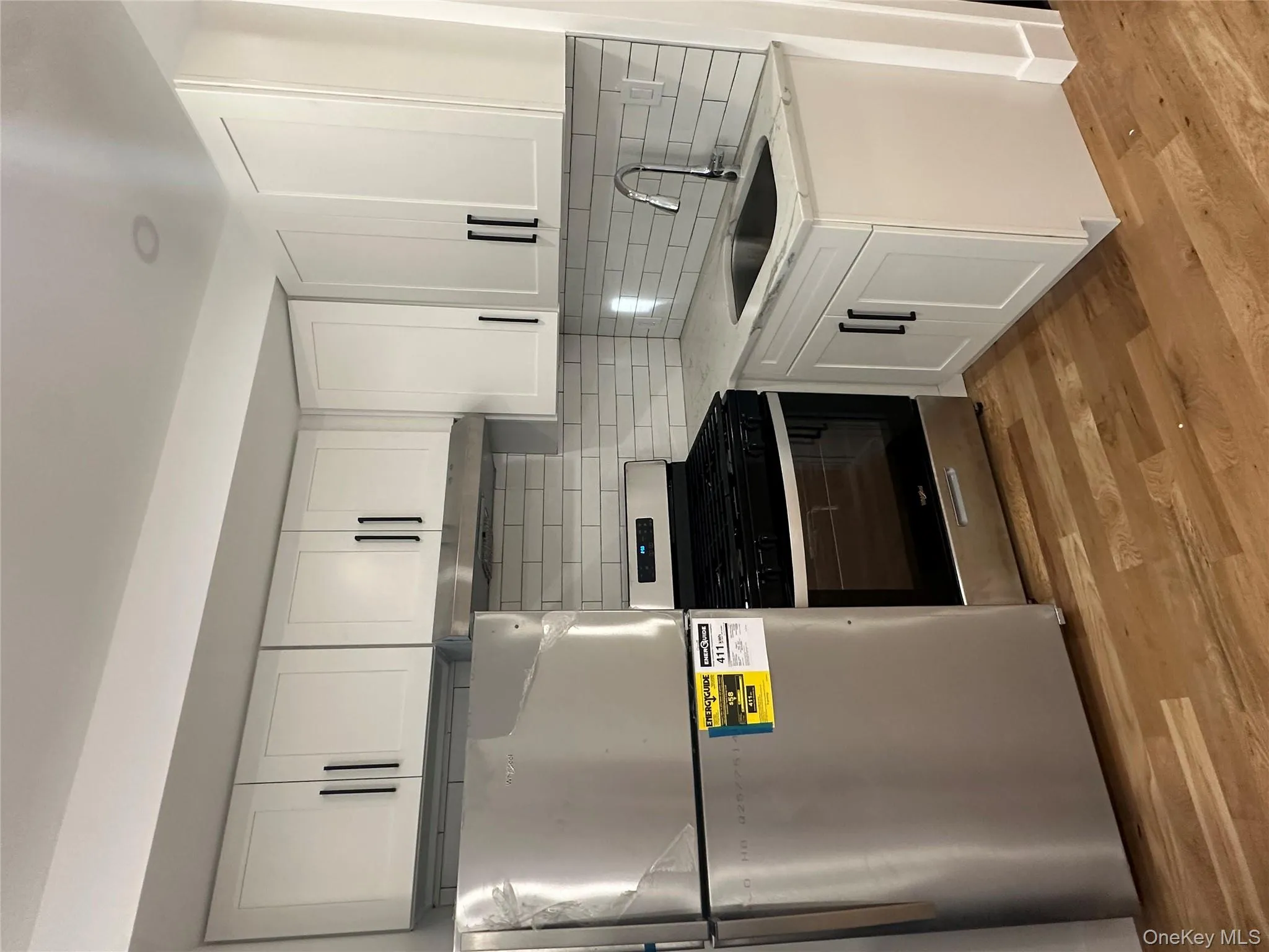 Kitchen with fridge, white cabinetry, stainless steel range, light stone countertops, and tasteful backsplash Kitchen with fridge, white cabinetry, stainless steel range, light stone countertops, and tasteful backsplash