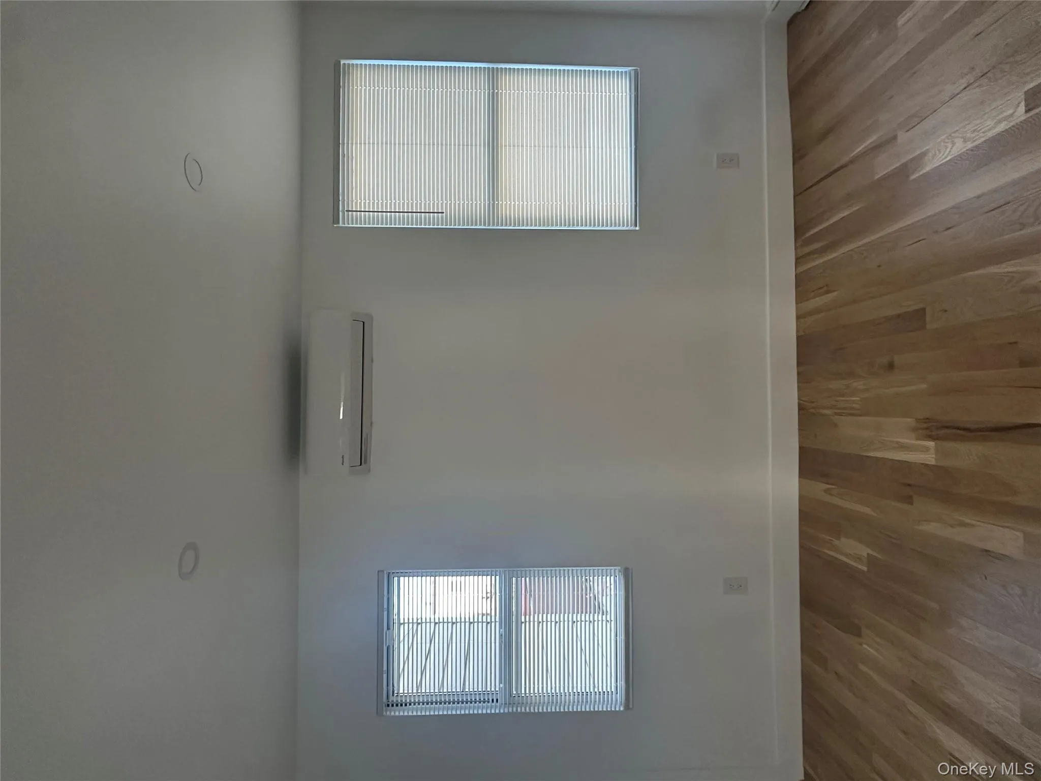 Unfurnished room featuring plenty of natural light, light wood-style flooring, and a wall unit AC Unfurnished room featuring plenty of natural light, light wood-style flooring, and a wall unit AC