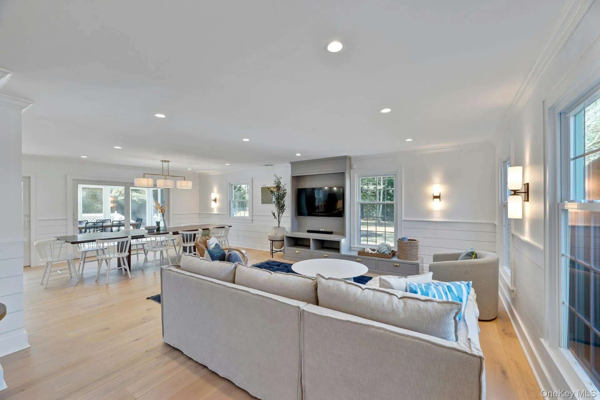 Living area with plenty of natural light, wainscoting, light wood-style flooring, crown molding, and recessed lighting Living area with plenty of natural light, wainscoting, light wood-style flooring, crown molding, and recessed lighting