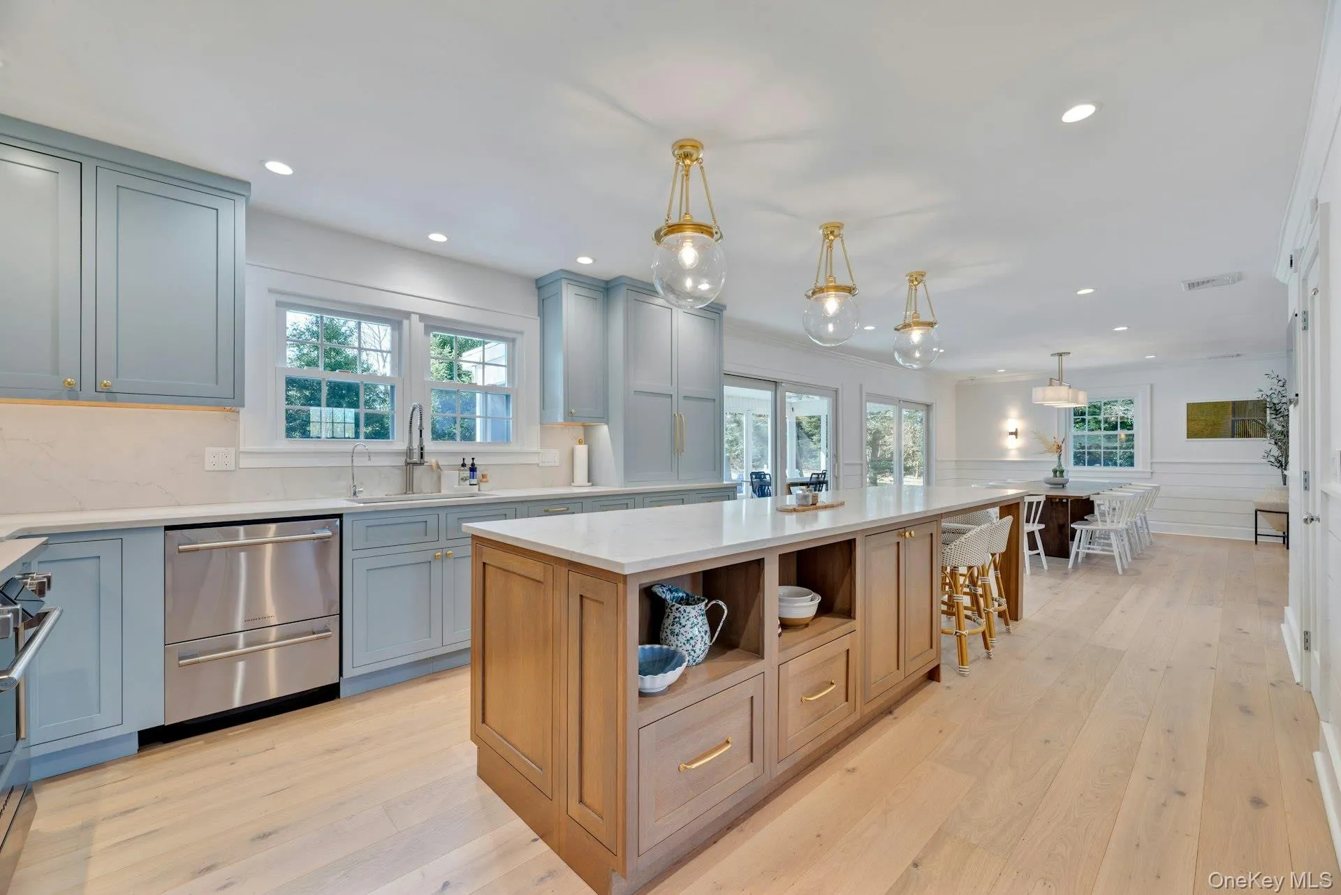 Kitchen featuring decorative light fixtures, open shelves, a kitchen island, light wood-style flooring, and a kitchen breakfast bar Kitchen featuring decorative light fixtures, open shelves, a kitchen island, light wood-style flooring, and a kitchen breakfast bar