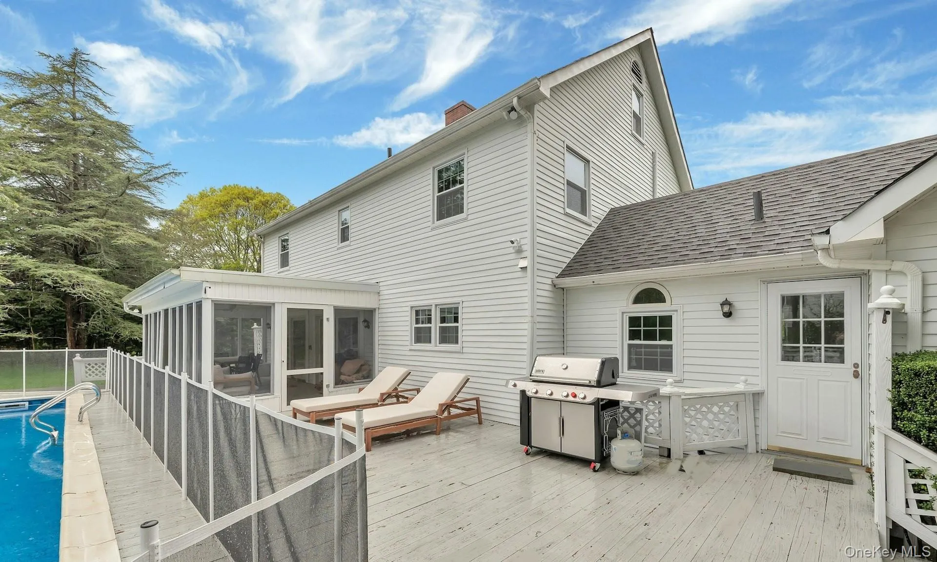 Rear view of house featuring a sunroom, a shingled roof, a deck, and a chimney Rear view of house featuring a sunroom, a shingled roof, a deck, and a chimney