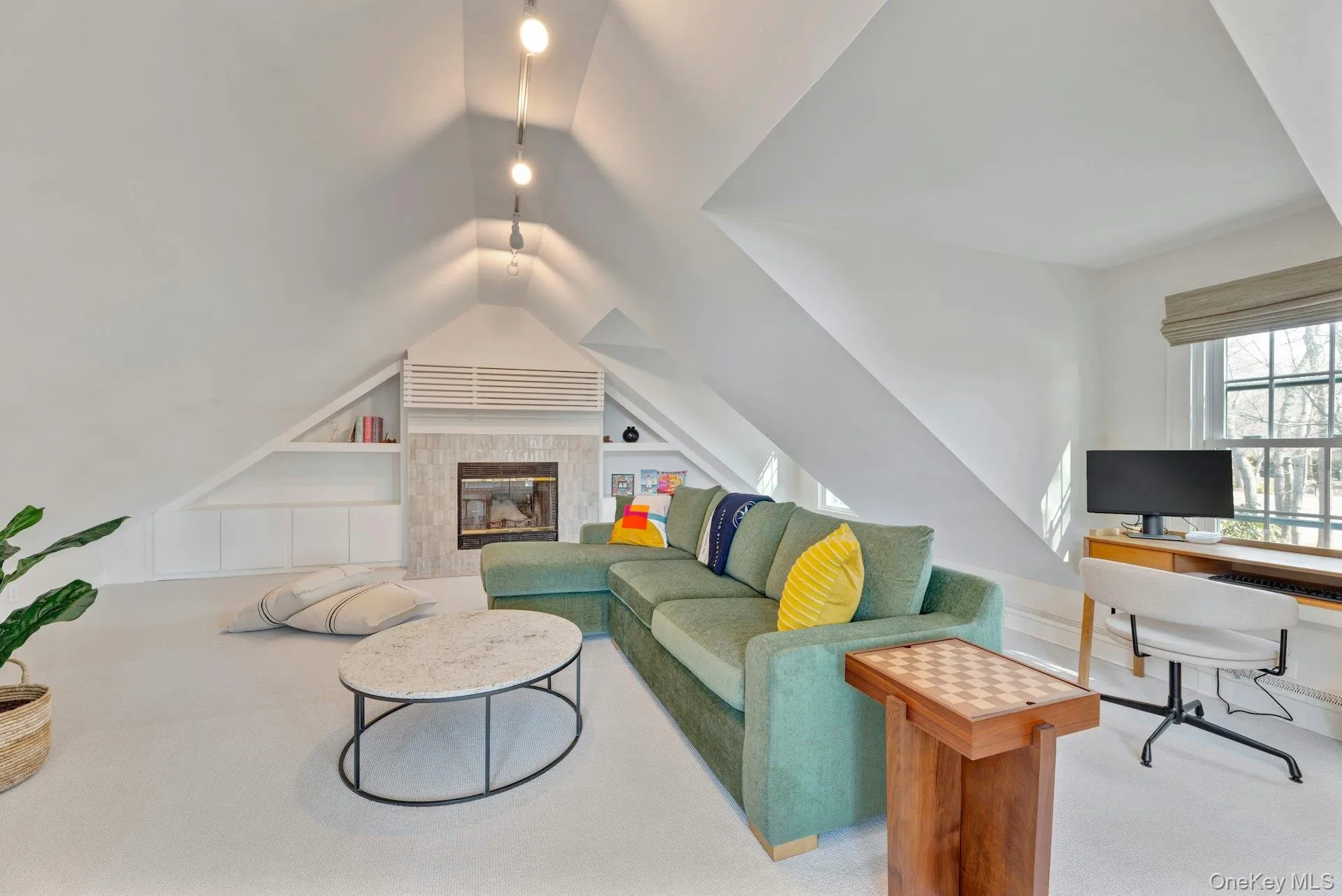 Carpeted living room with built in shelves, an office area, and lofted ceiling Carpeted living room with built in shelves, an office area, and lofted ceiling