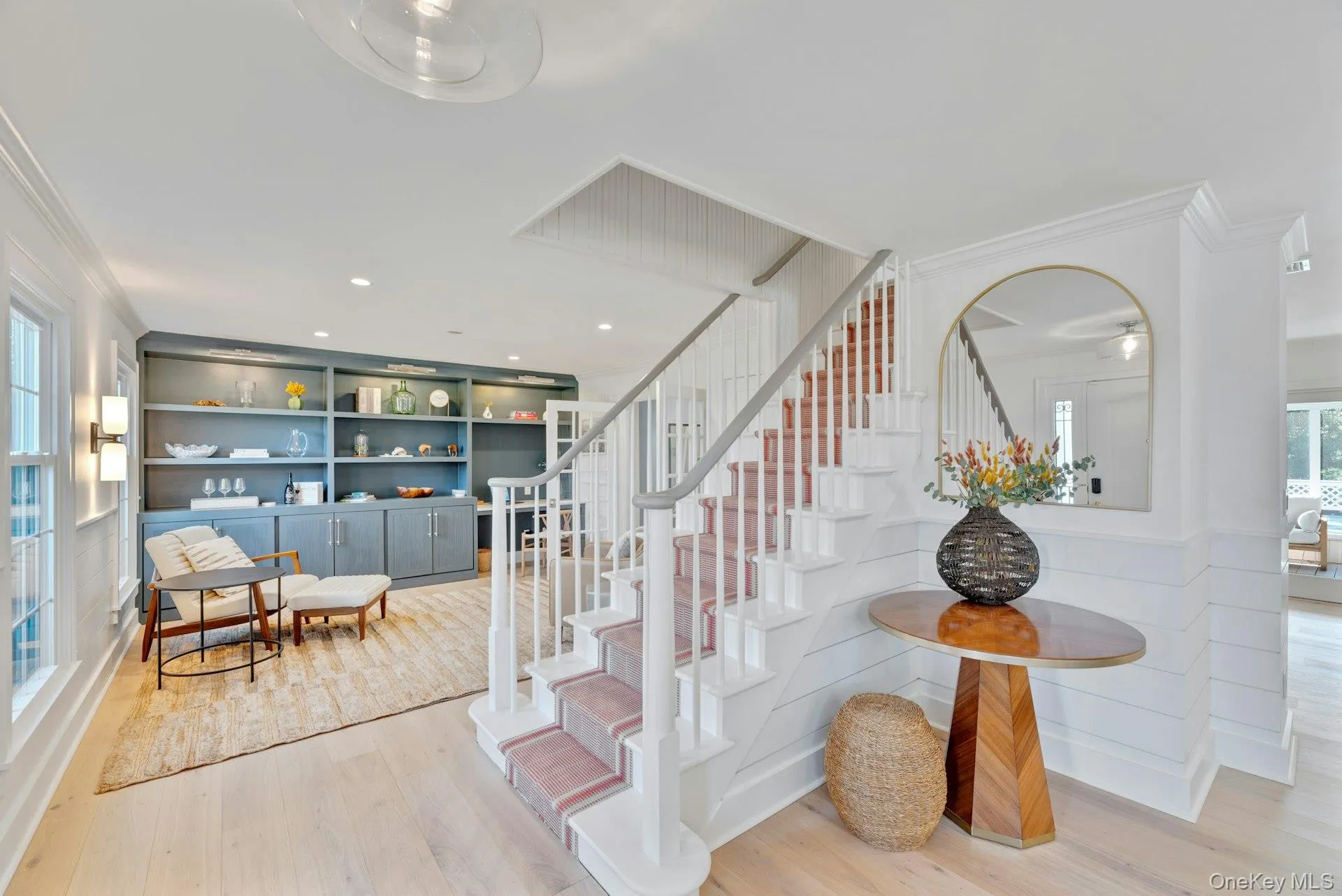 Stairs featuring plenty of natural light, ornamental molding, wood finished floors, and built in shelves Stairs featuring plenty of natural light, ornamental molding, wood finished floors, and built in shelves