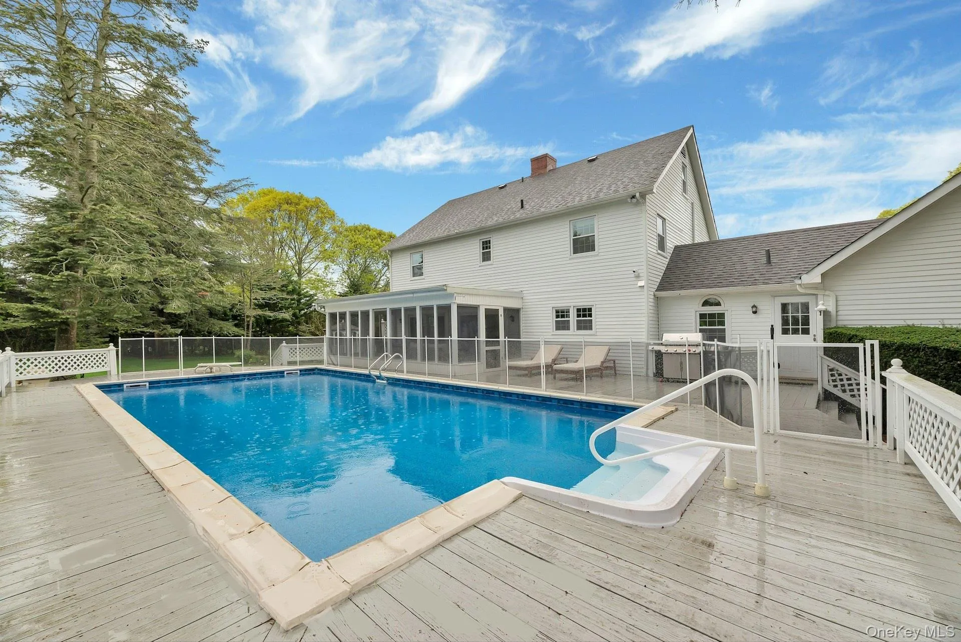 View of pool with a sunroom and a wooden deck View of pool with a sunroom and a wooden deck