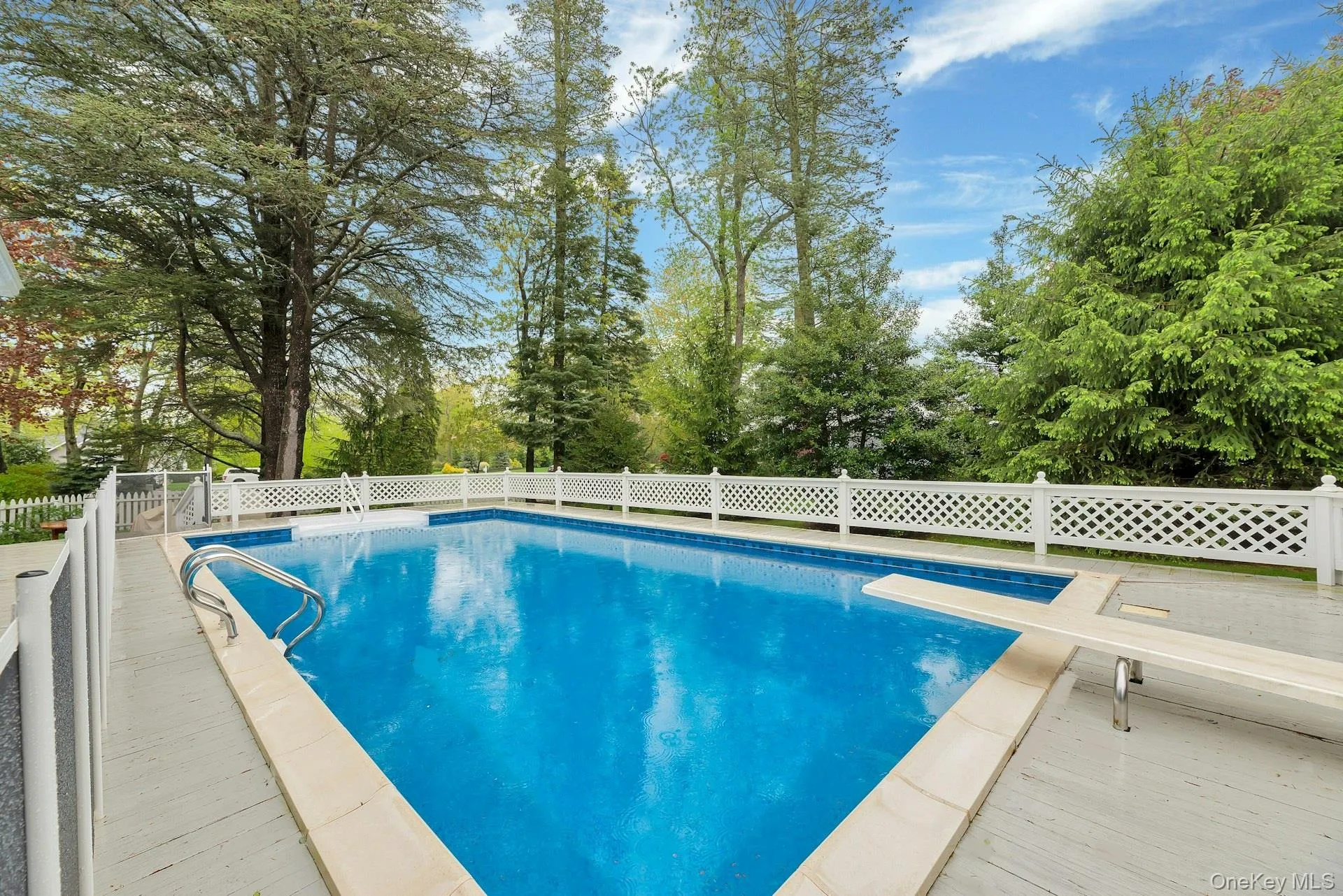 View of swimming pool with a diving board, a fenced backyard, and a patio area View of swimming pool with a diving board, a fenced backyard, and a patio area