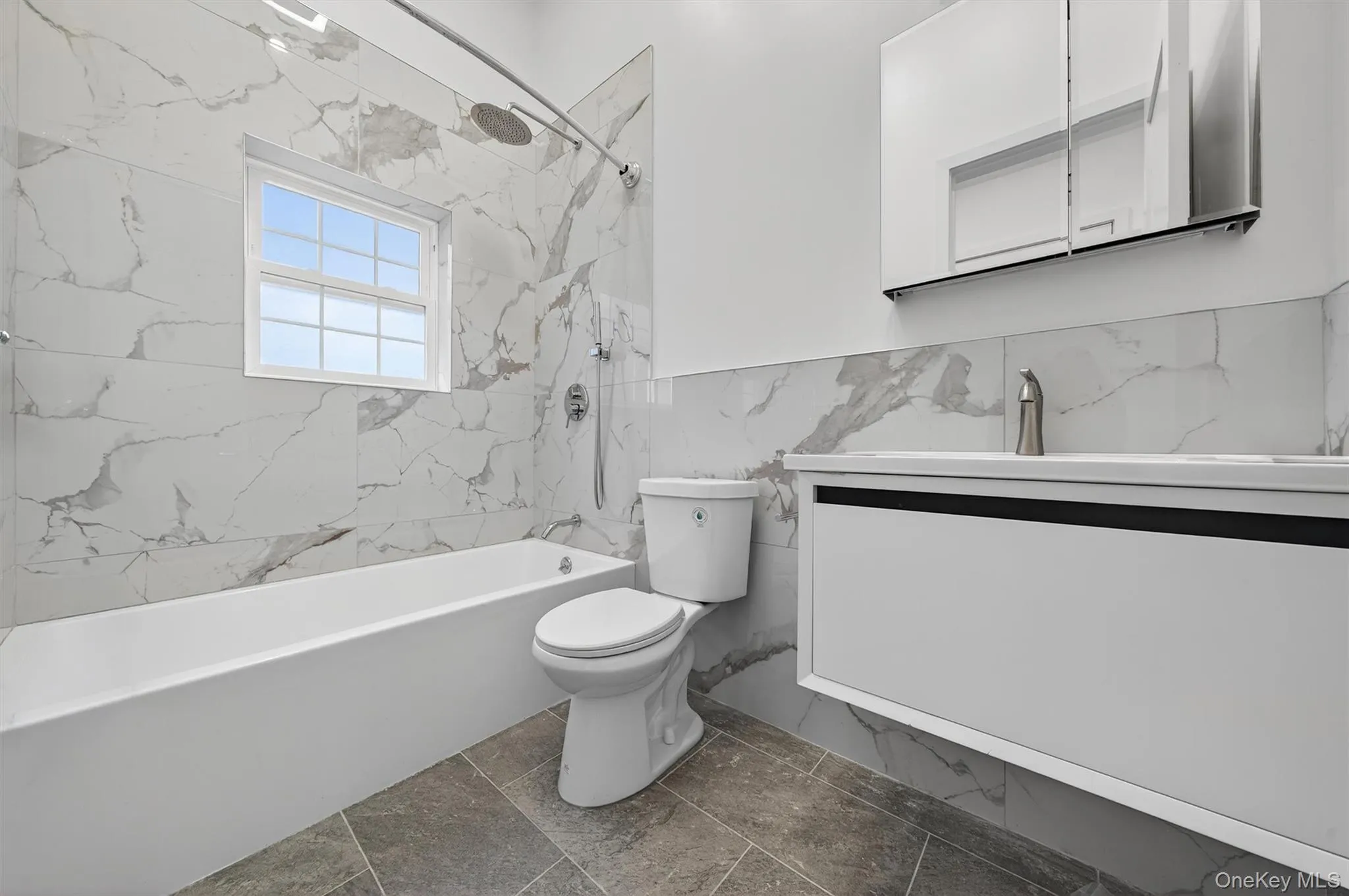Bathroom with vanity, a combined bath / shower with marble appearance, tile walls, and a wainscoted wall Bathroom with vanity, a combined bath / shower with marble appearance, tile walls, and a wainscoted wall