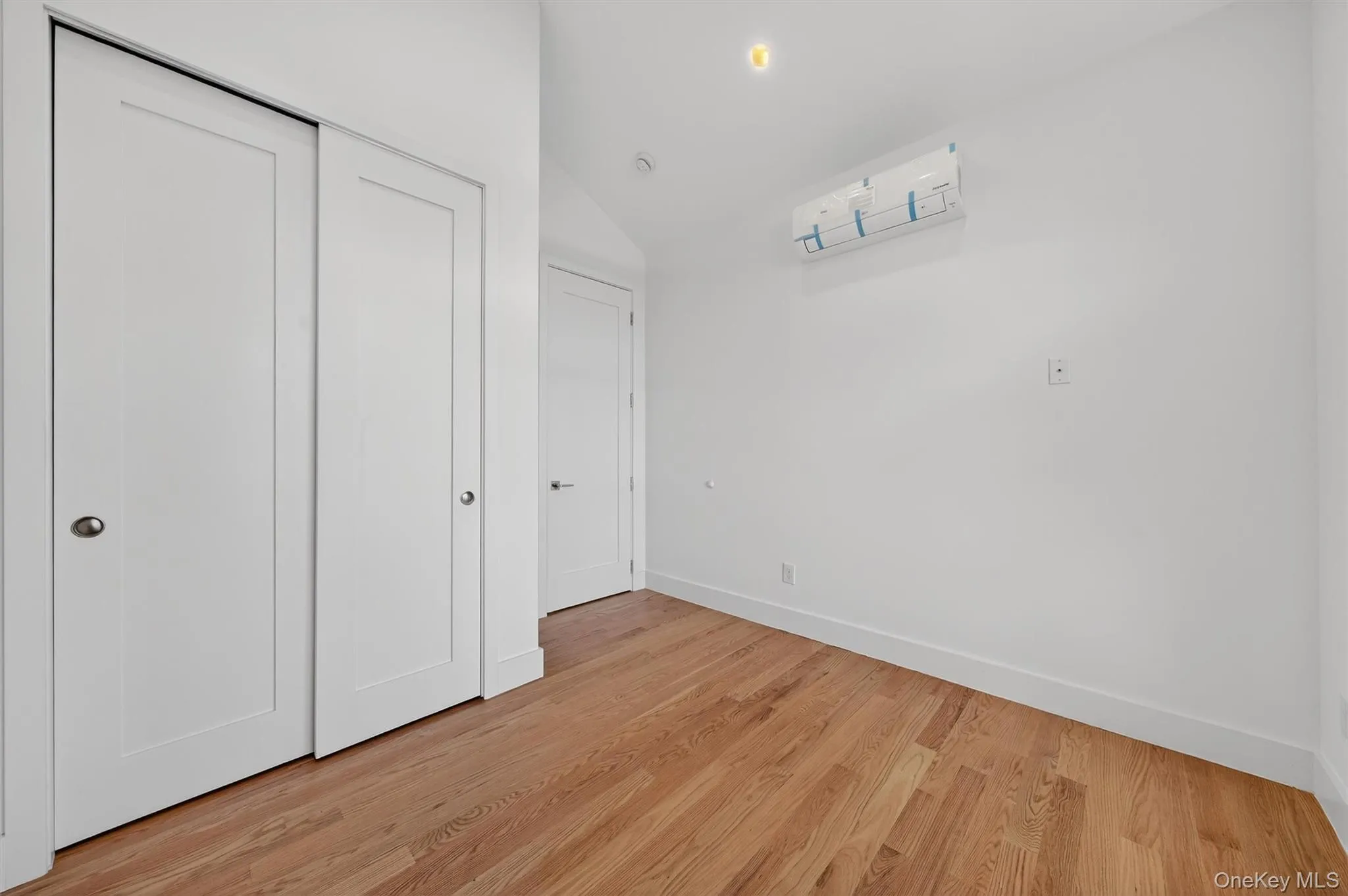 Unfurnished bedroom with lofted ceiling, a closet, light wood finished floors, and recessed lighting Unfurnished bedroom with lofted ceiling, a closet, light wood finished floors, and recessed lighting