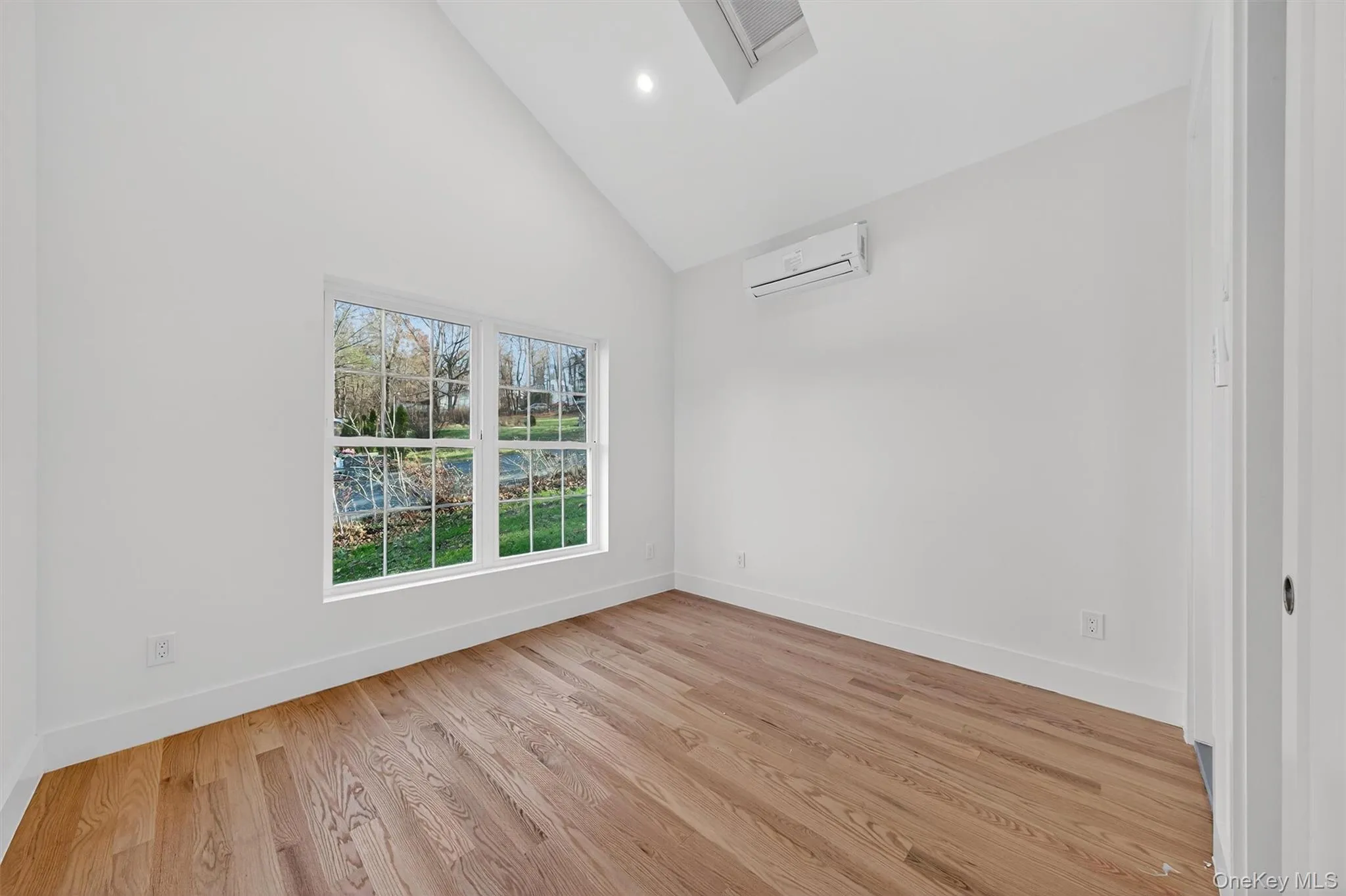 Unfurnished room featuring high vaulted ceiling, light wood-style floors, recessed lighting, and a wall unit AC Unfurnished room featuring high vaulted ceiling, light wood-style floors, recessed lighting, and a wall unit AC