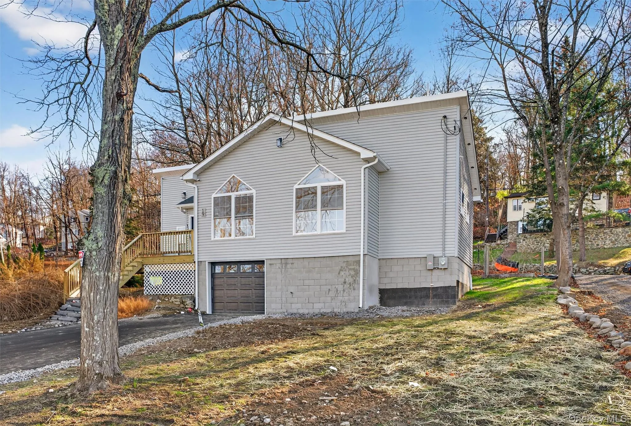 View of side of home with stairs, a deck, driveway, and an attached garage View of side of home with stairs, a deck, driveway, and an attached garage