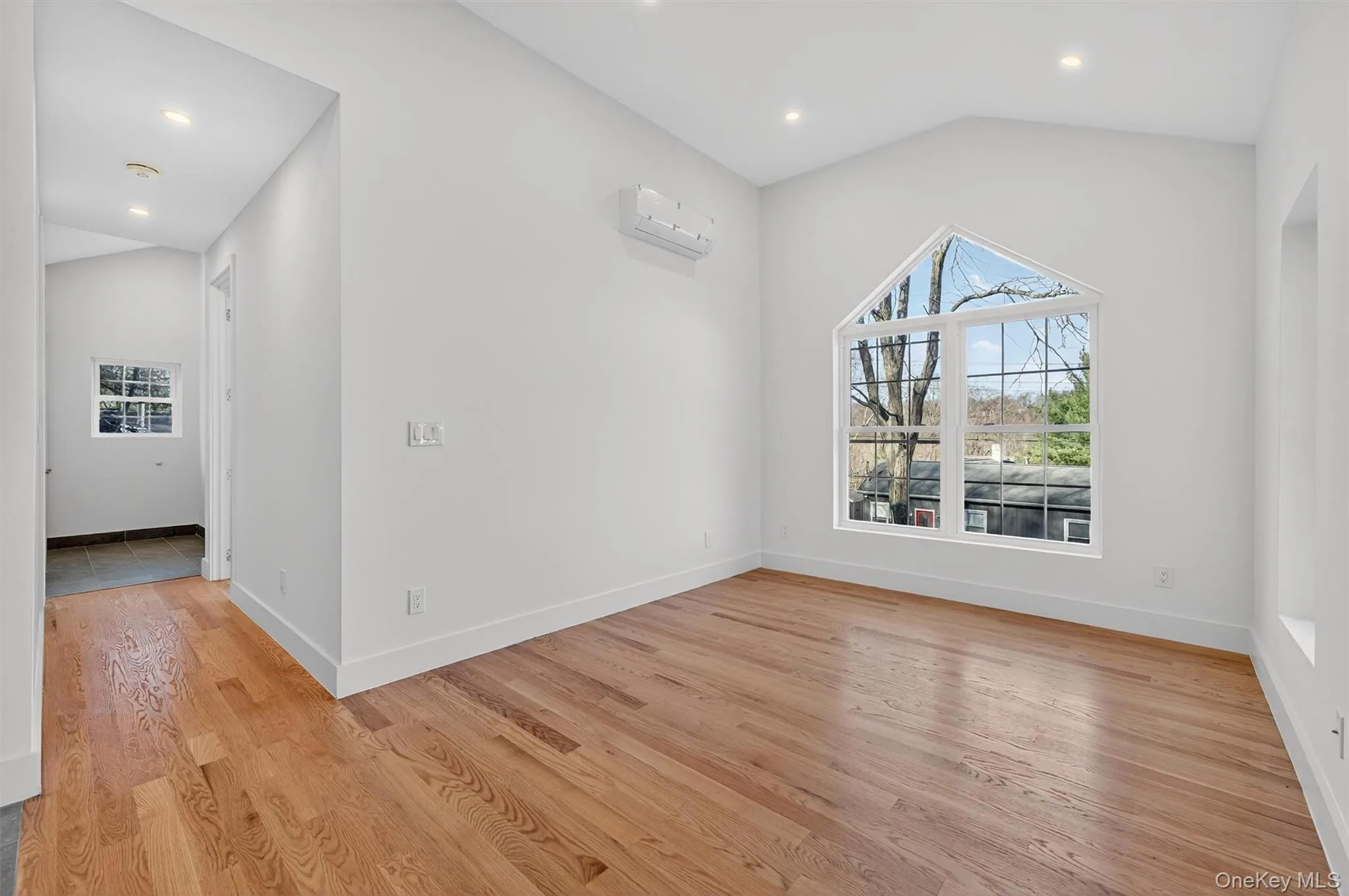 Unfurnished room with lofted ceiling, light wood finished floors, and recessed lighting Unfurnished room with lofted ceiling, light wood finished floors, and recessed lighting