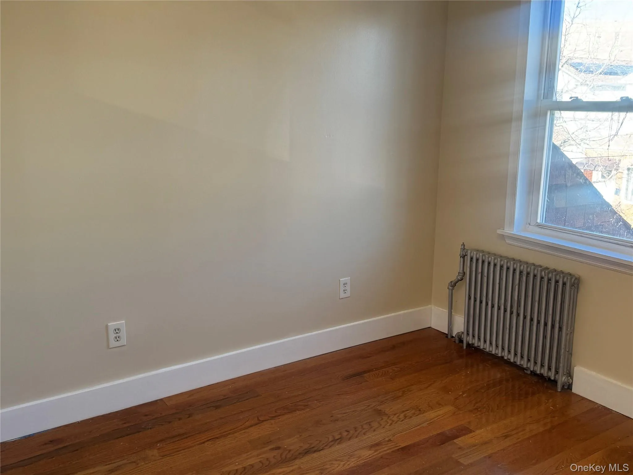 Spare room with radiator heating unit and dark wood finished floors Spare room with radiator heating unit and dark wood finished floors