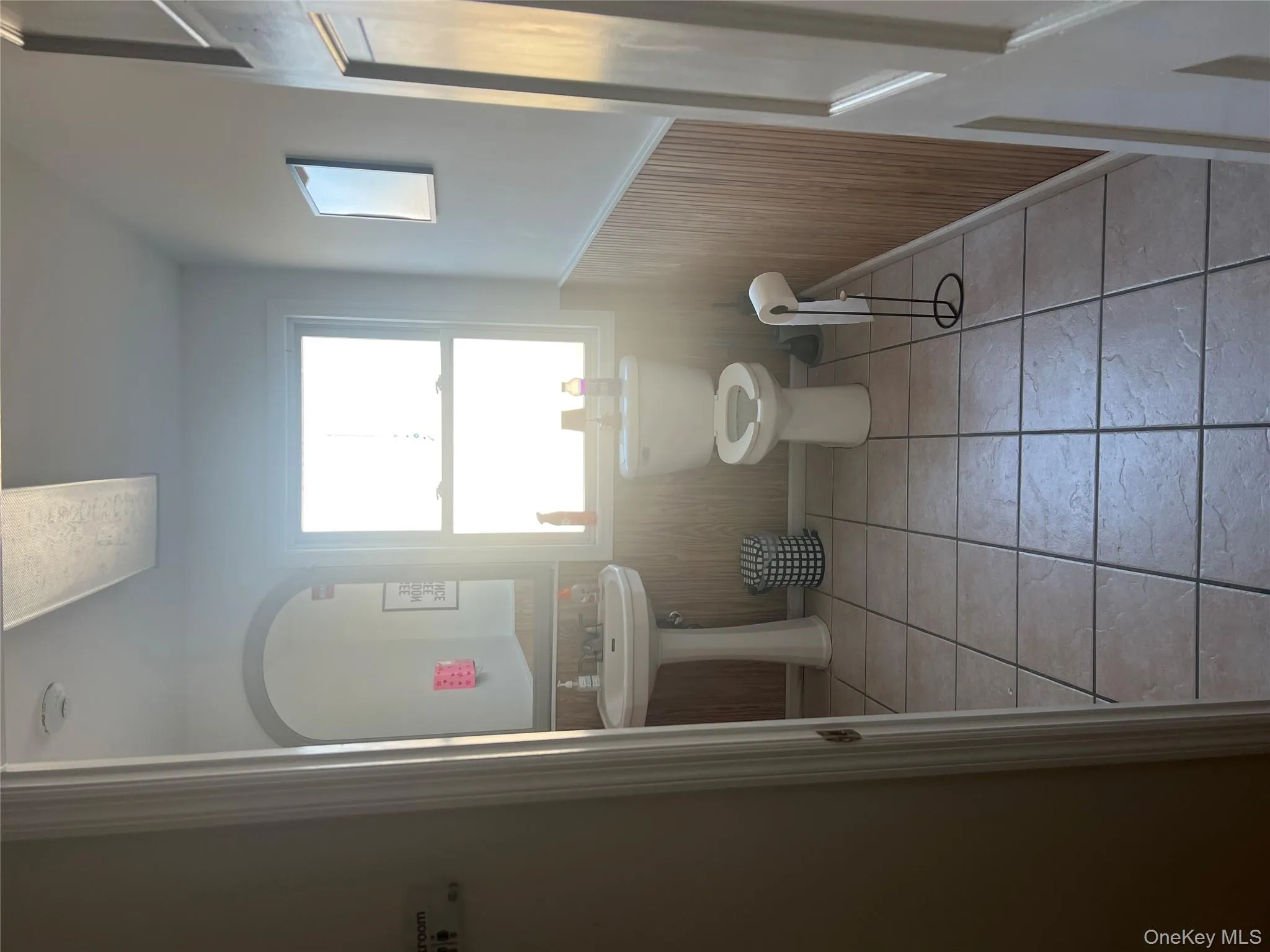 Half bathroom featuring a wainscoted wall, wooden walls, and light tile patterned flooring Half bathroom featuring a wainscoted wall, wooden walls, and light tile patterned flooring