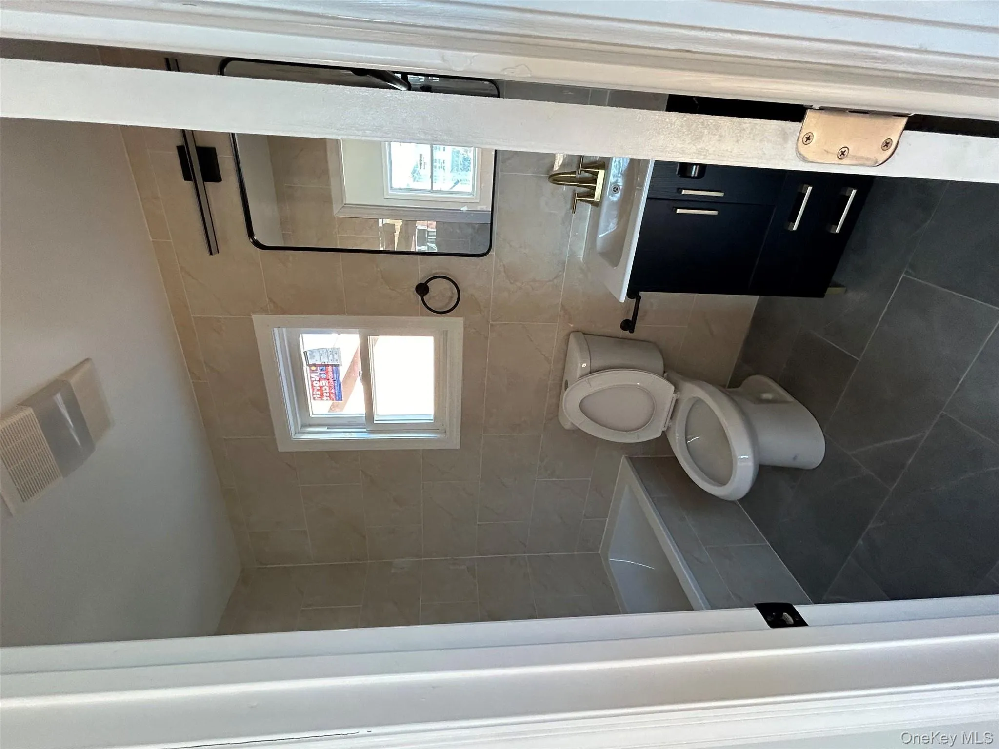 Full bathroom featuring tile walls, vanity, and dark tile patterned floors Full bathroom featuring tile walls, vanity, and dark tile patterned floors