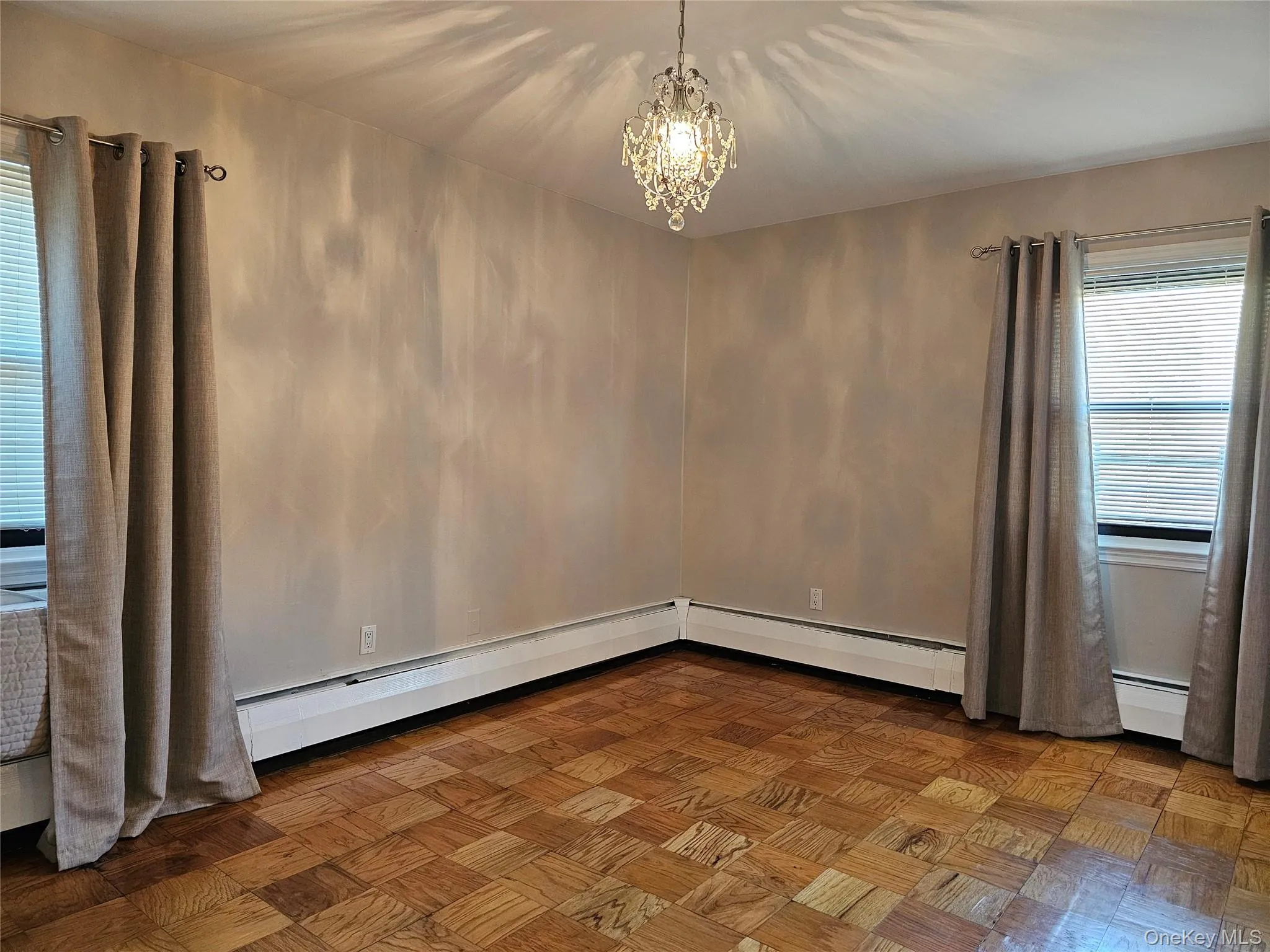 Empty room with a chandelier and baseboard heating Empty room with a chandelier and baseboard heating