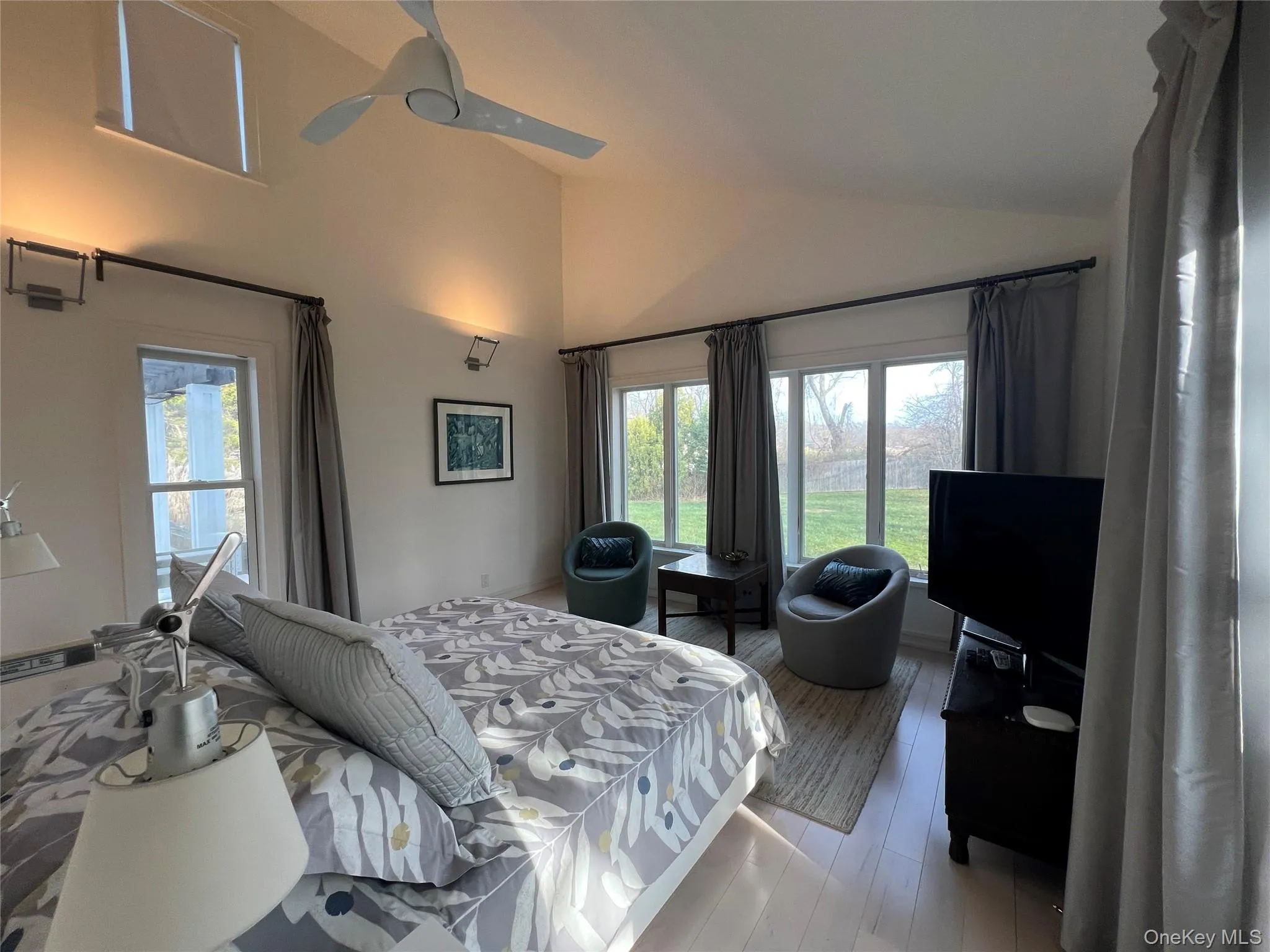 PrimaryBedroom featuring a ceiling fan, wood- flooring, and high vaulted ceiling PrimaryBedroom featuring a ceiling fan, wood- flooring, and high vaulted ceiling